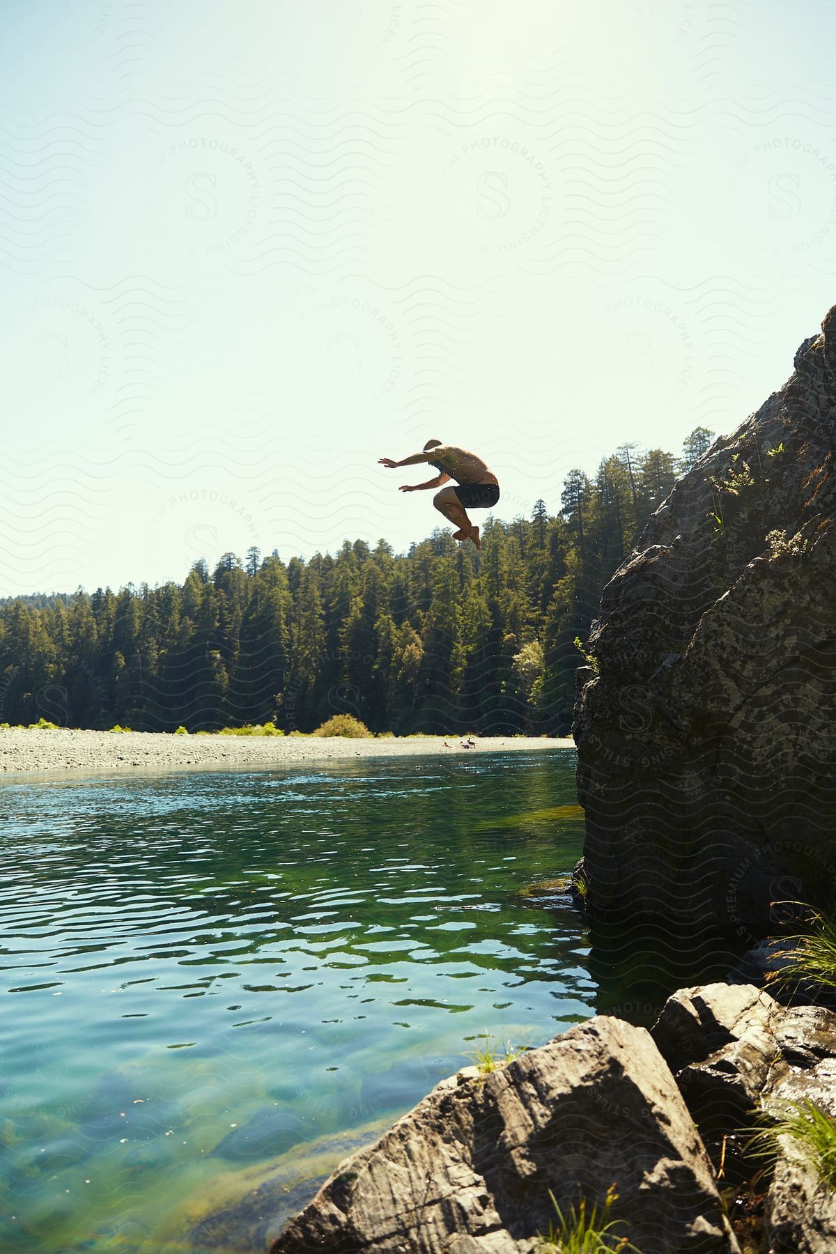 Natural scene of a person free falling towards a lake with conifers in a forest around.