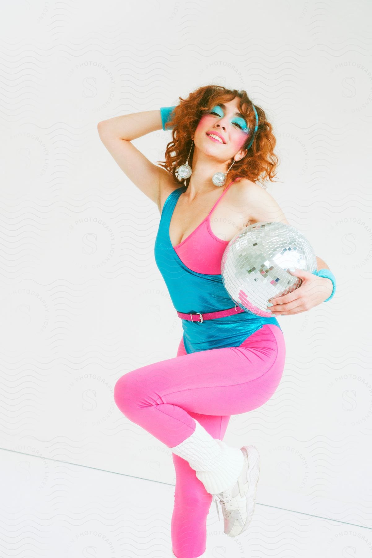 A pretty woman in bright clothing posing while holding a disco ball