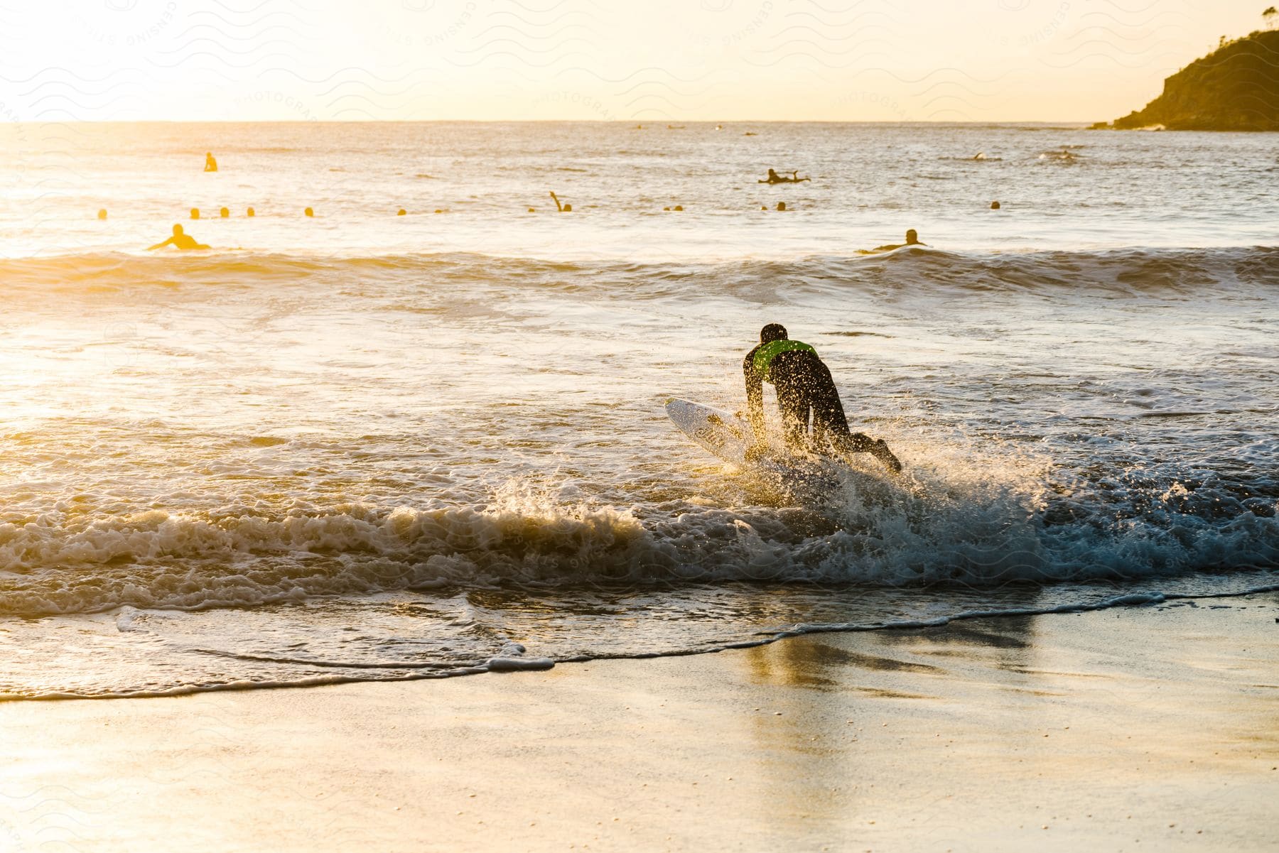 Surfer enters the water as waves crash against the beach.