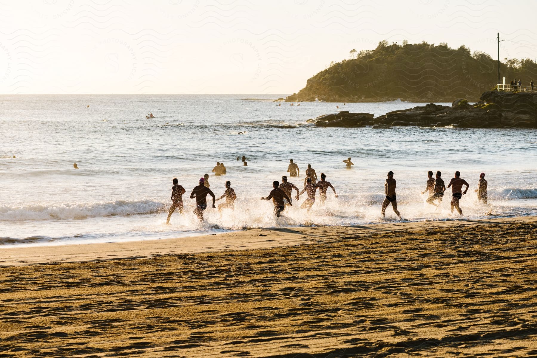 Group of people running and entering the sea on the beach in the late afternoon