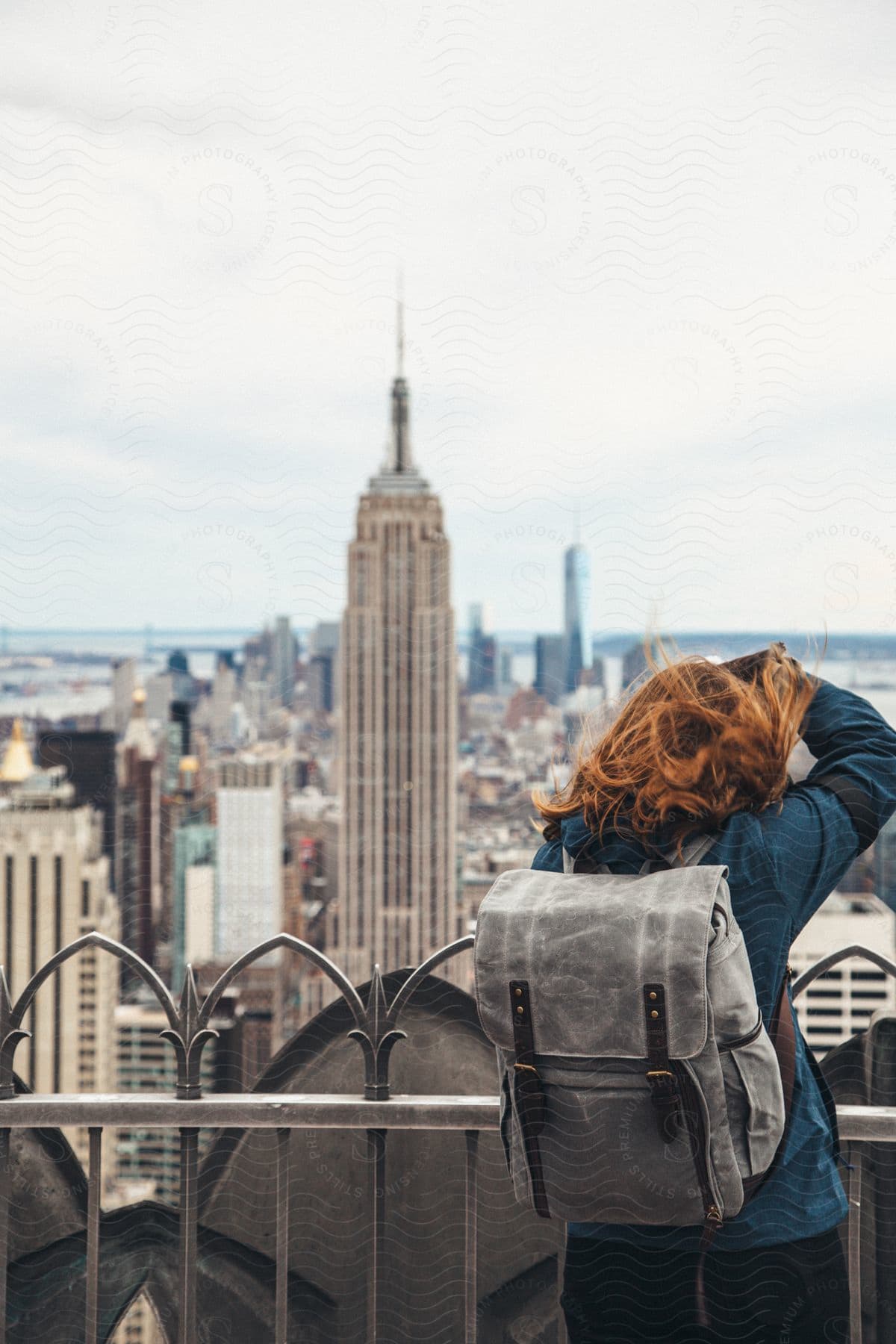 A woman stands on an observation deck that overlooks the Empire State Building.