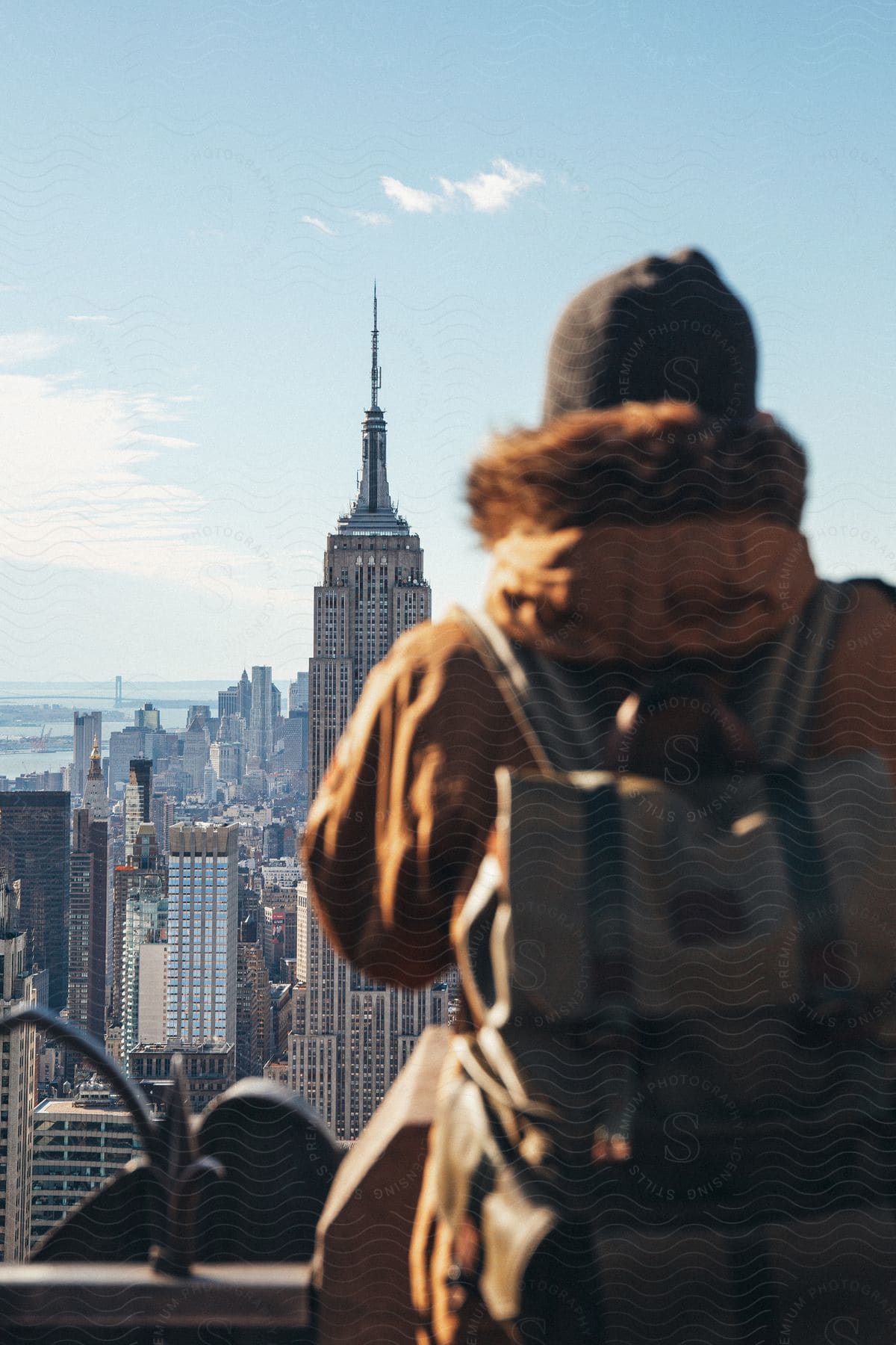 Person wearing backpack stands looking at the city surrounding the Empire State Building.
