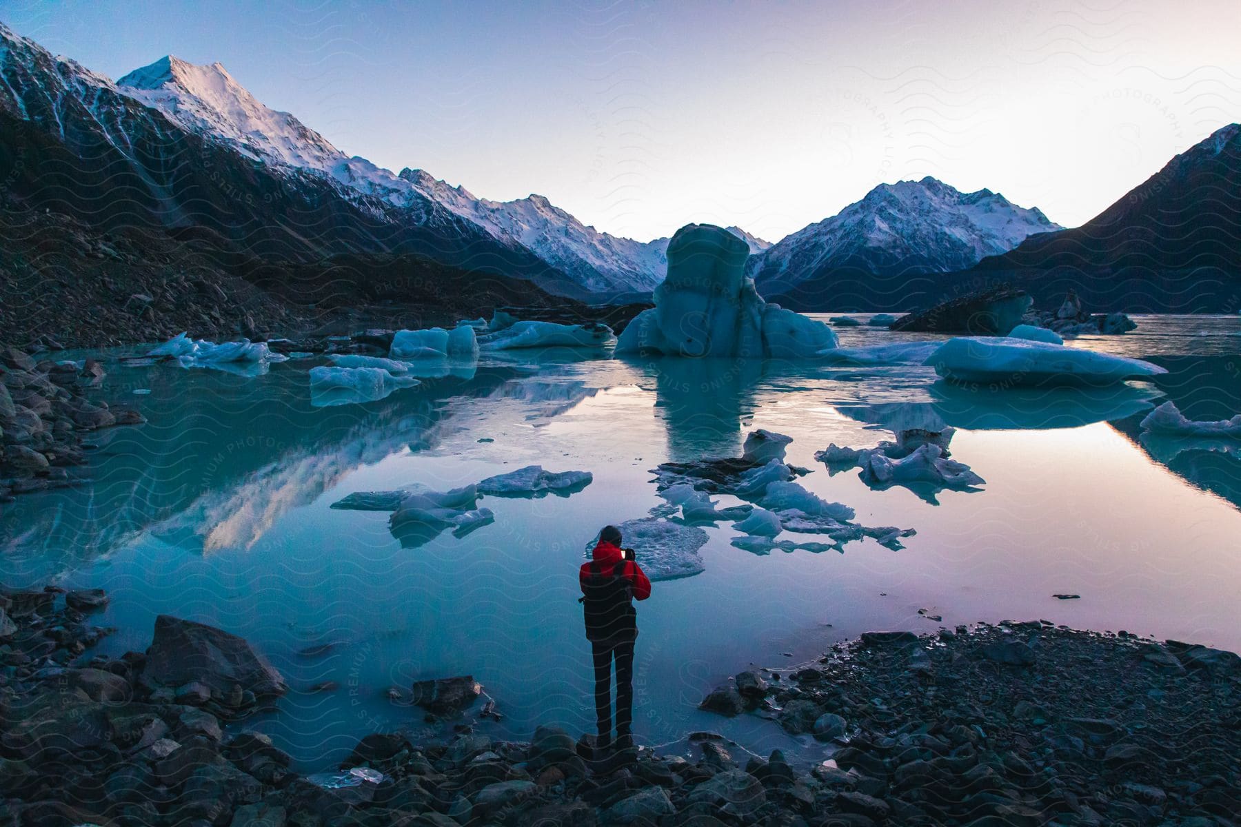 A person standing along the edge of a lake full of ice in the arctic