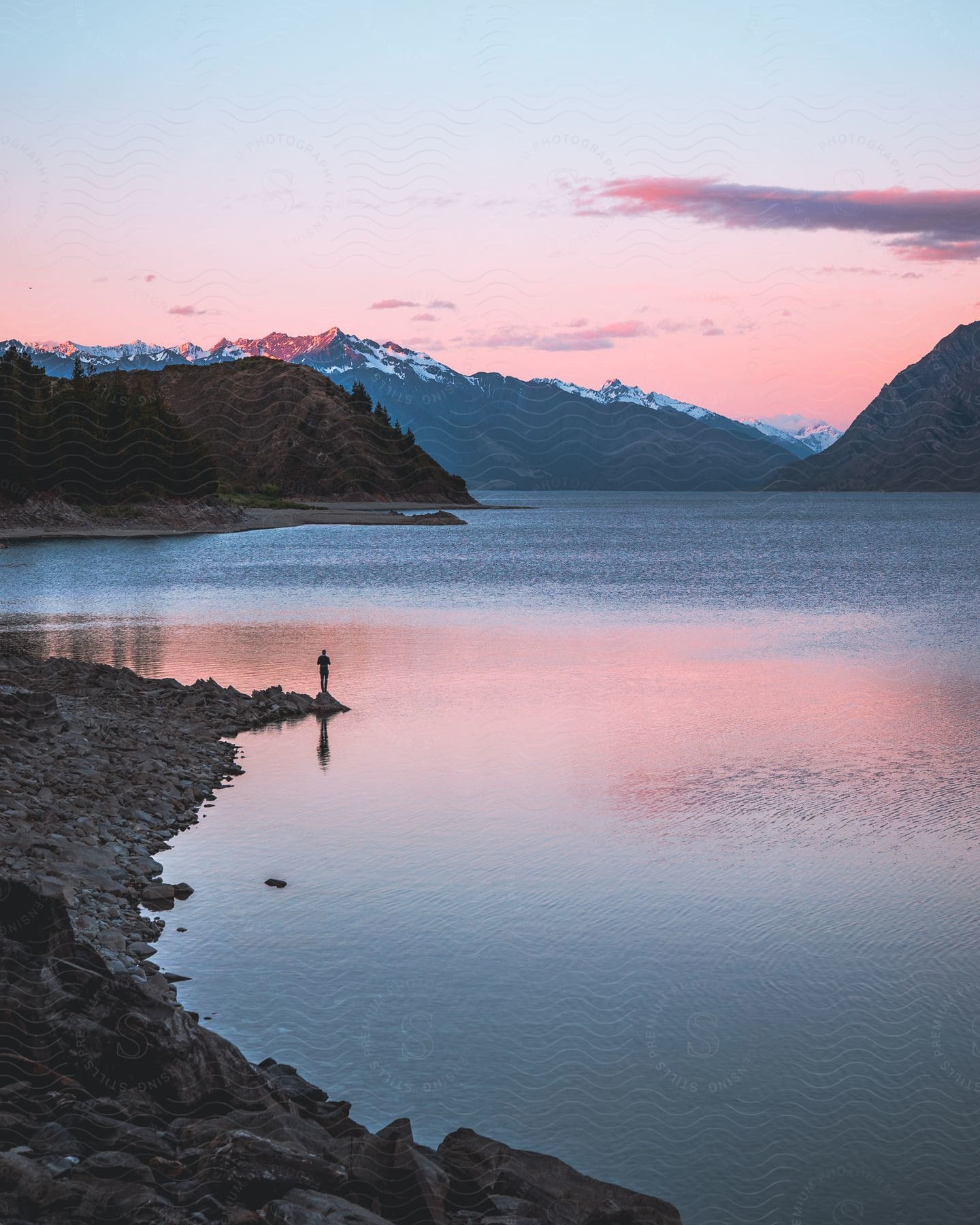 A person fishing outdoors at sunrise.