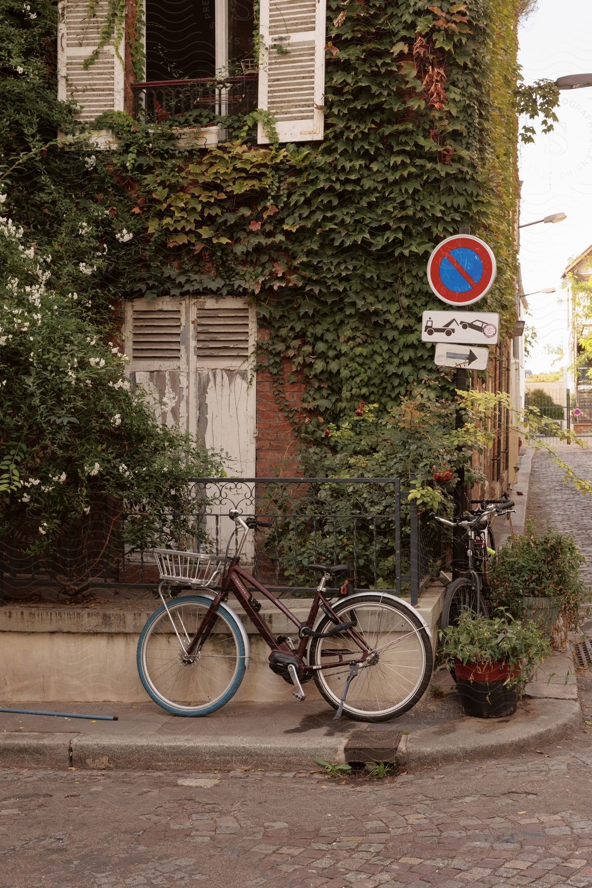 Bicycles parked near a run down corner building with potted plants on the sidewalk