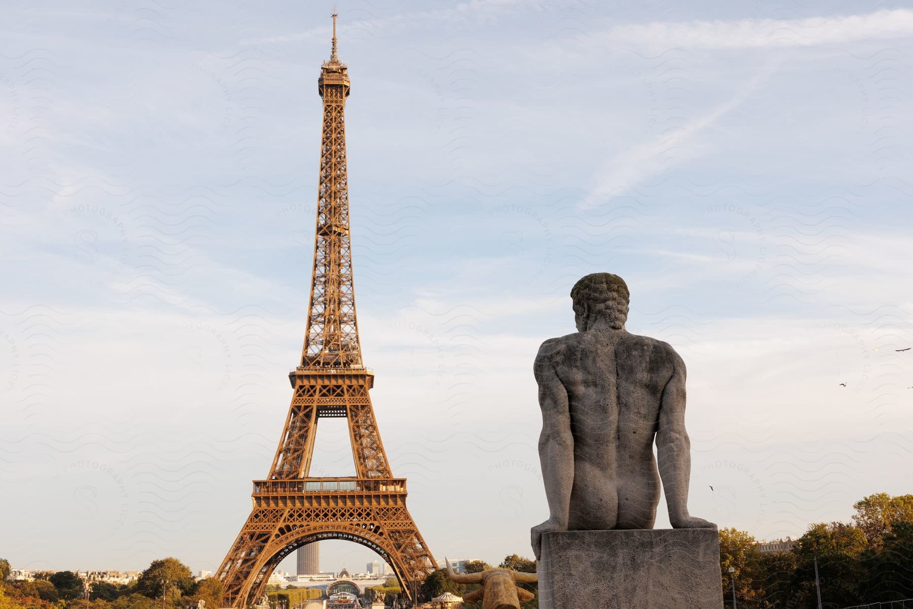 Sculpture of a naked man in front of the Eiffel Tower