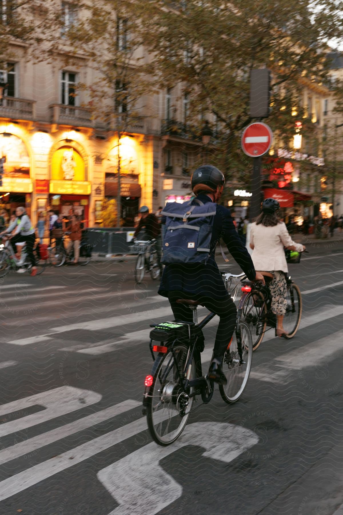 An asphalt street with some people riding bicycles wearing helmets