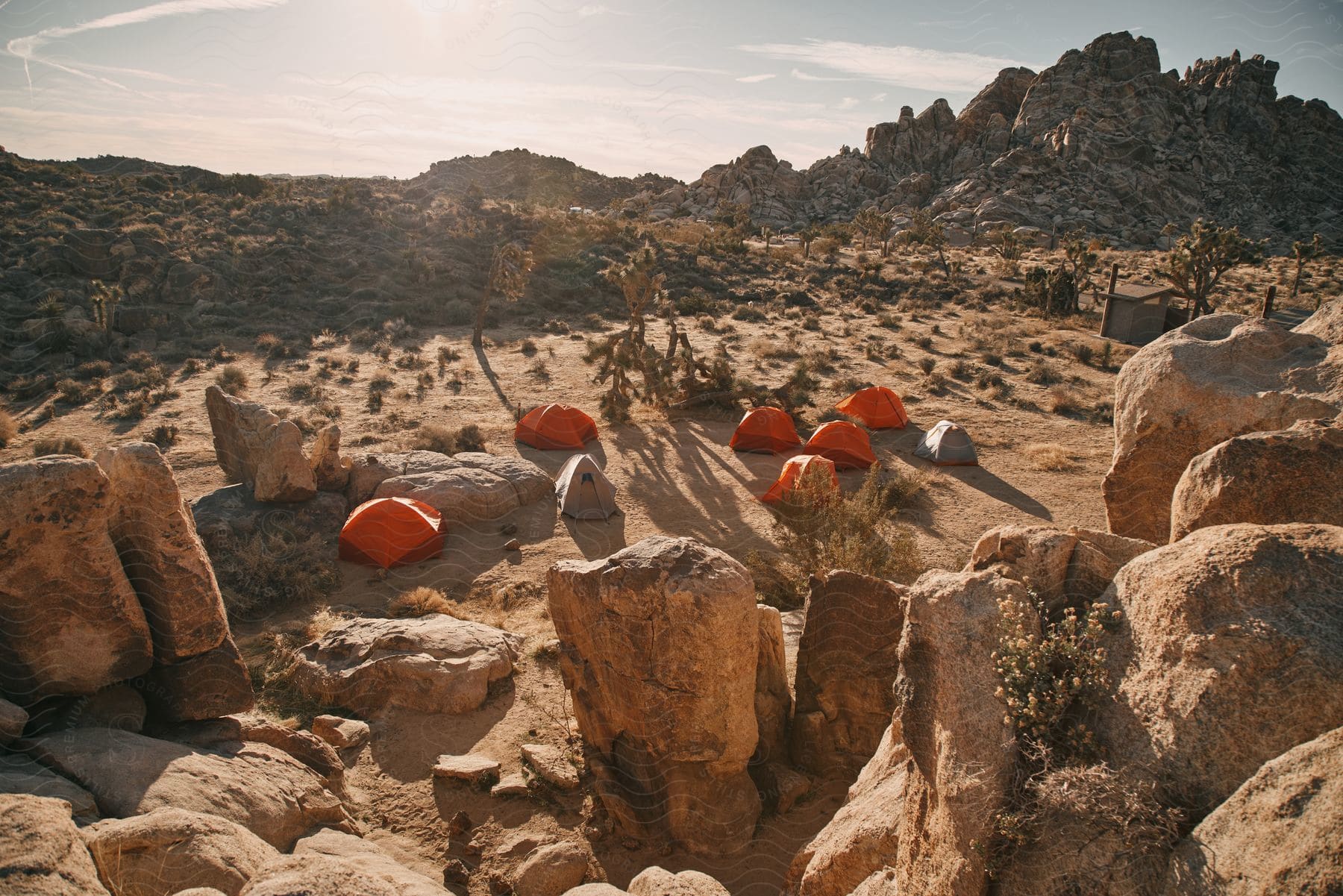 Several orange and silver tents dotting rugged terrain.