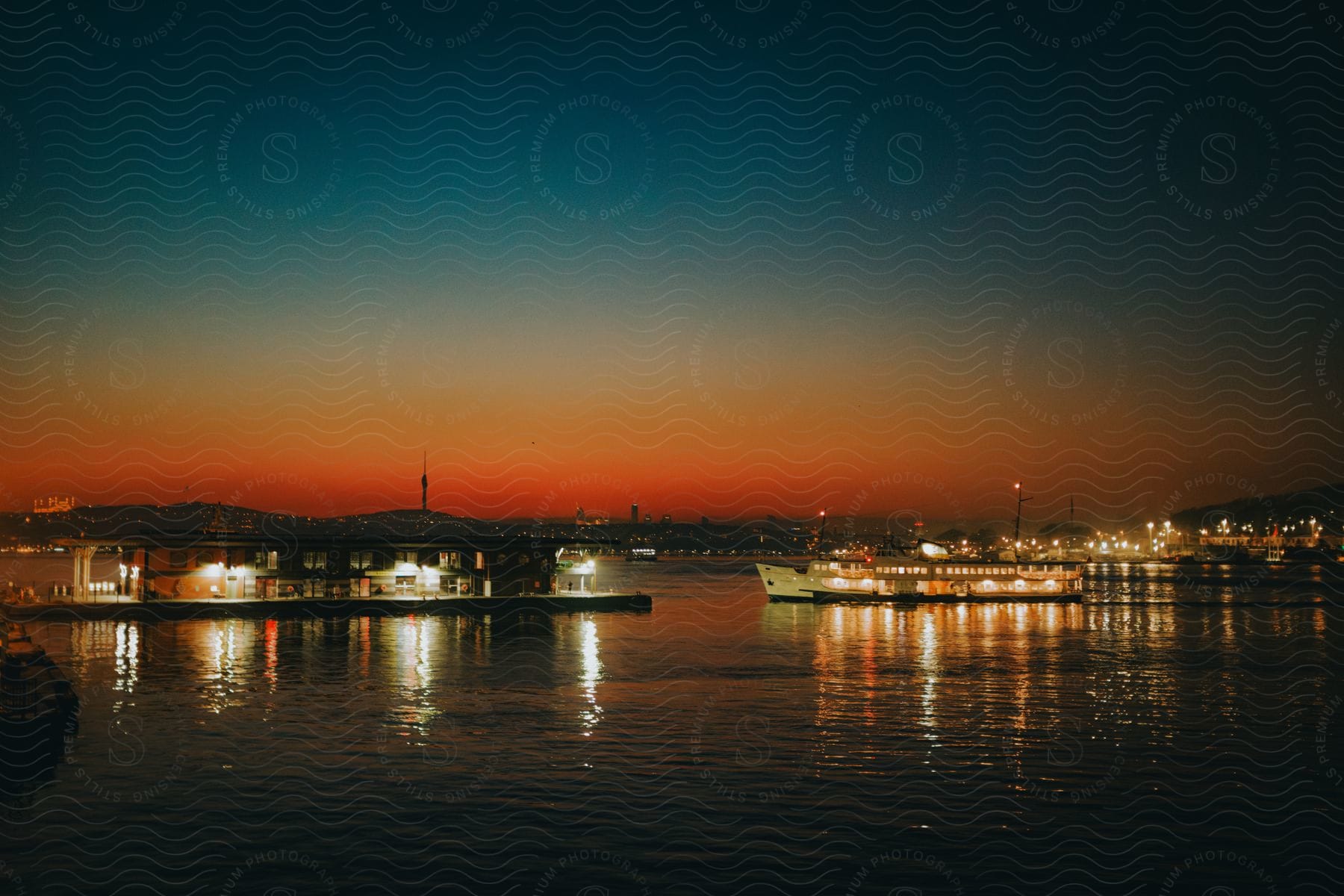 Bright boats sit at dock across the water from the city silhouetted against the red afterglow at night.