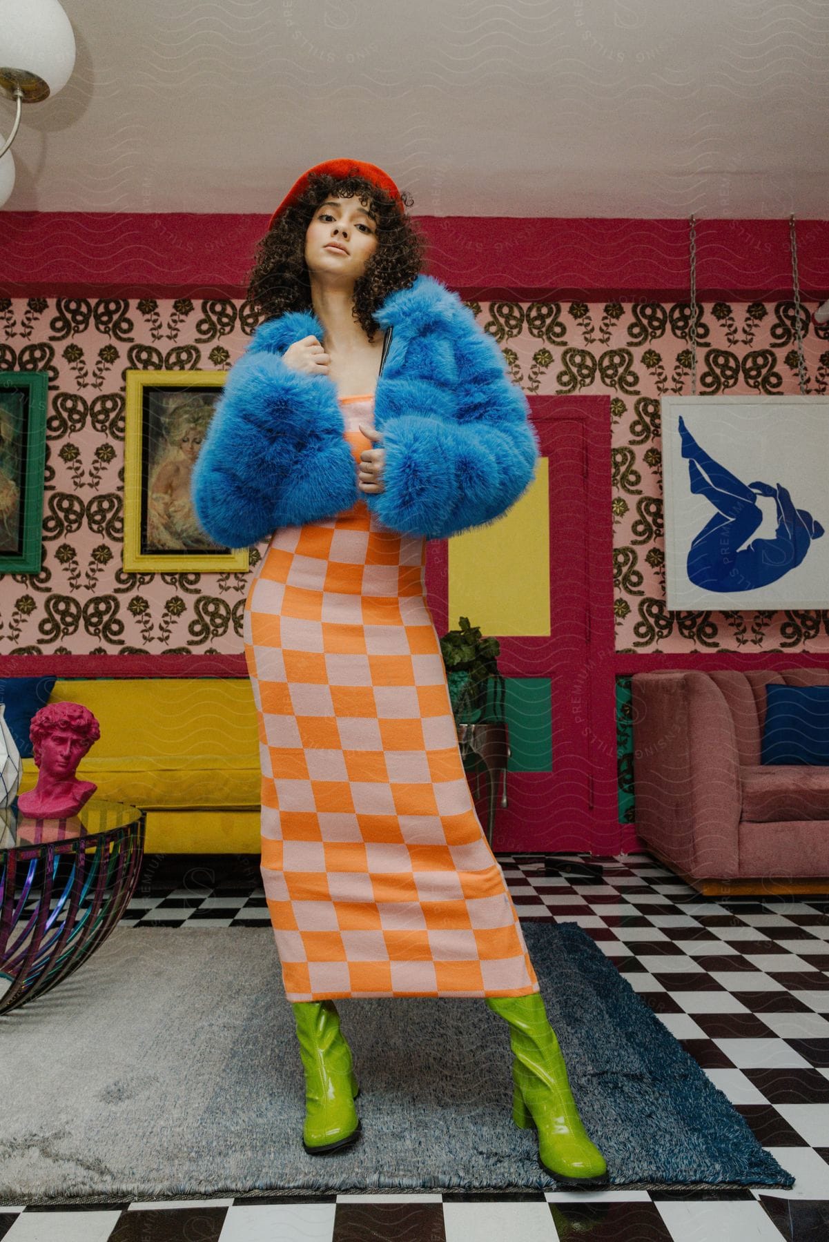 Woman standing wearing a checkered dress and blue fur coat with chartreuse green boots