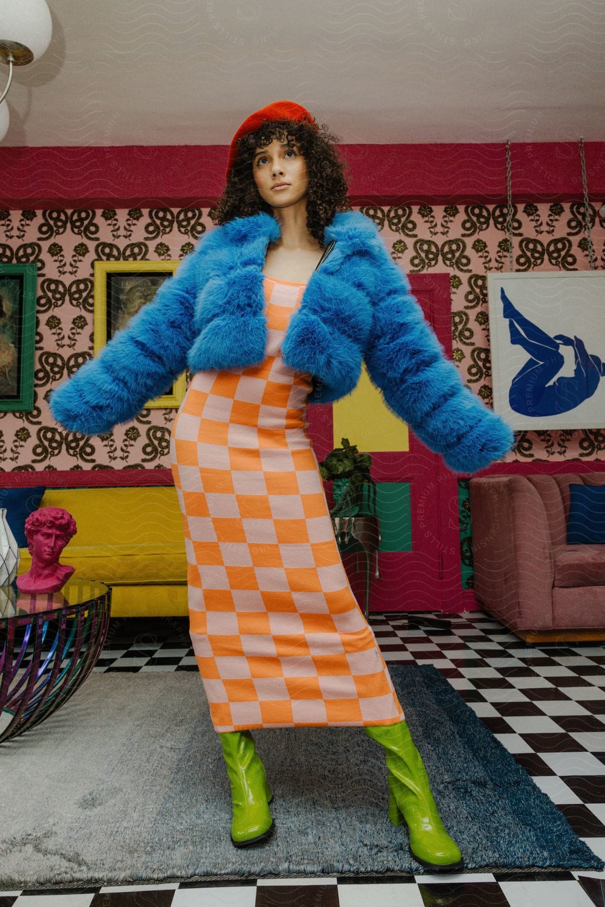 Woman standing wearing a checkered dress and blue fur coat with chartreuse green boots