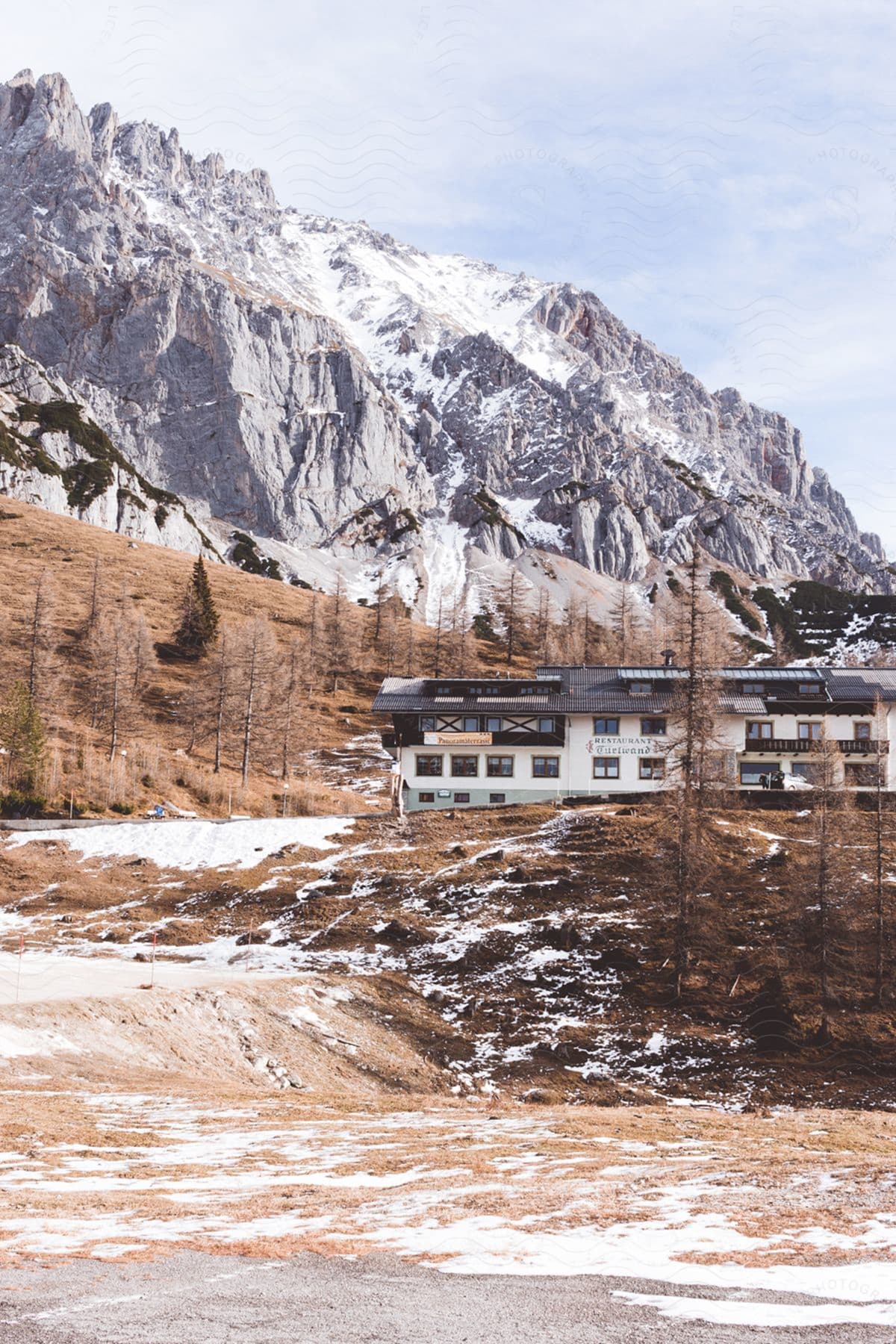 Hotel on a hill next to snow-covered mountain ranges.