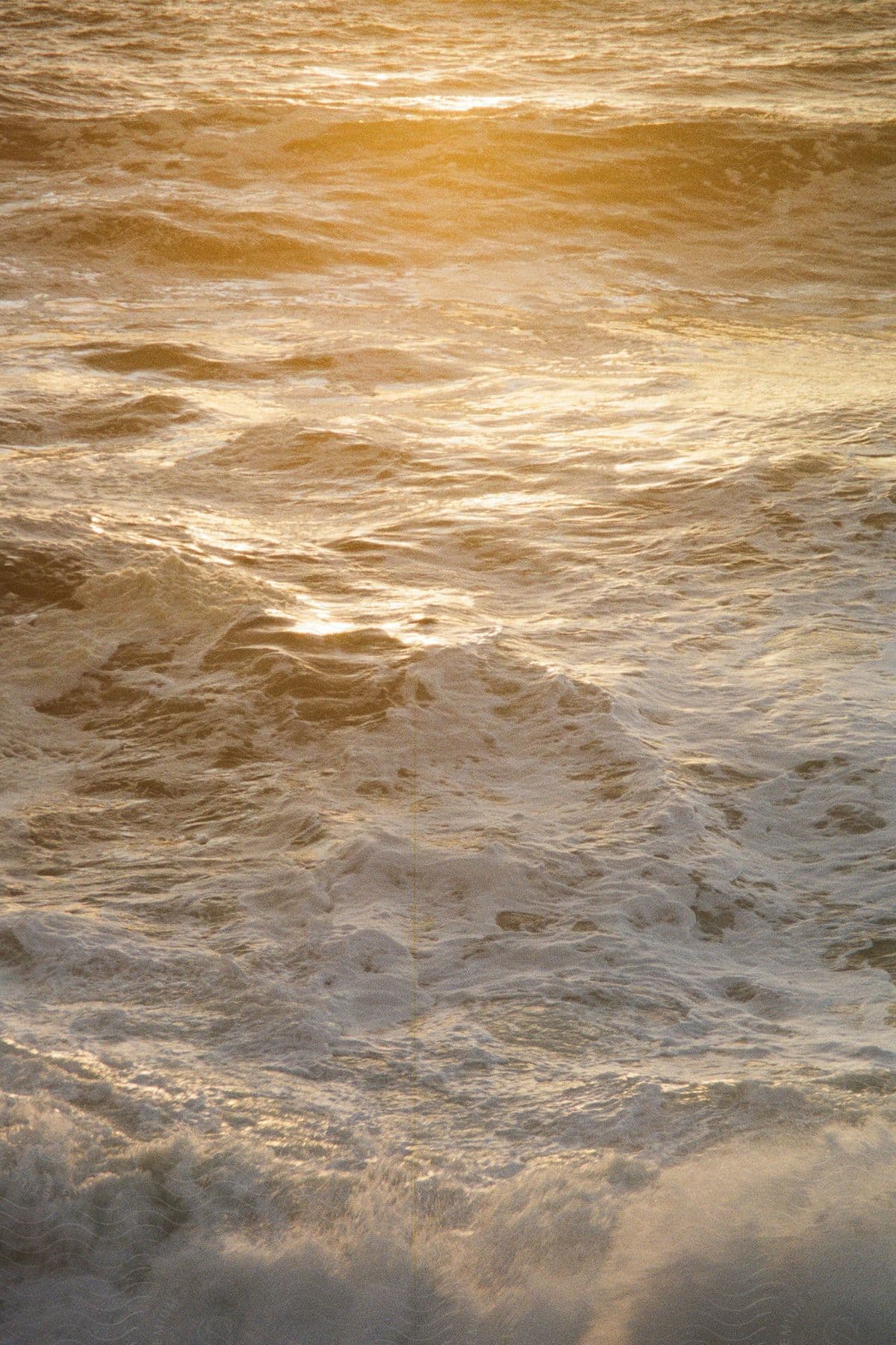 Golden sun at dawn shining on foaming breaking ocean waves