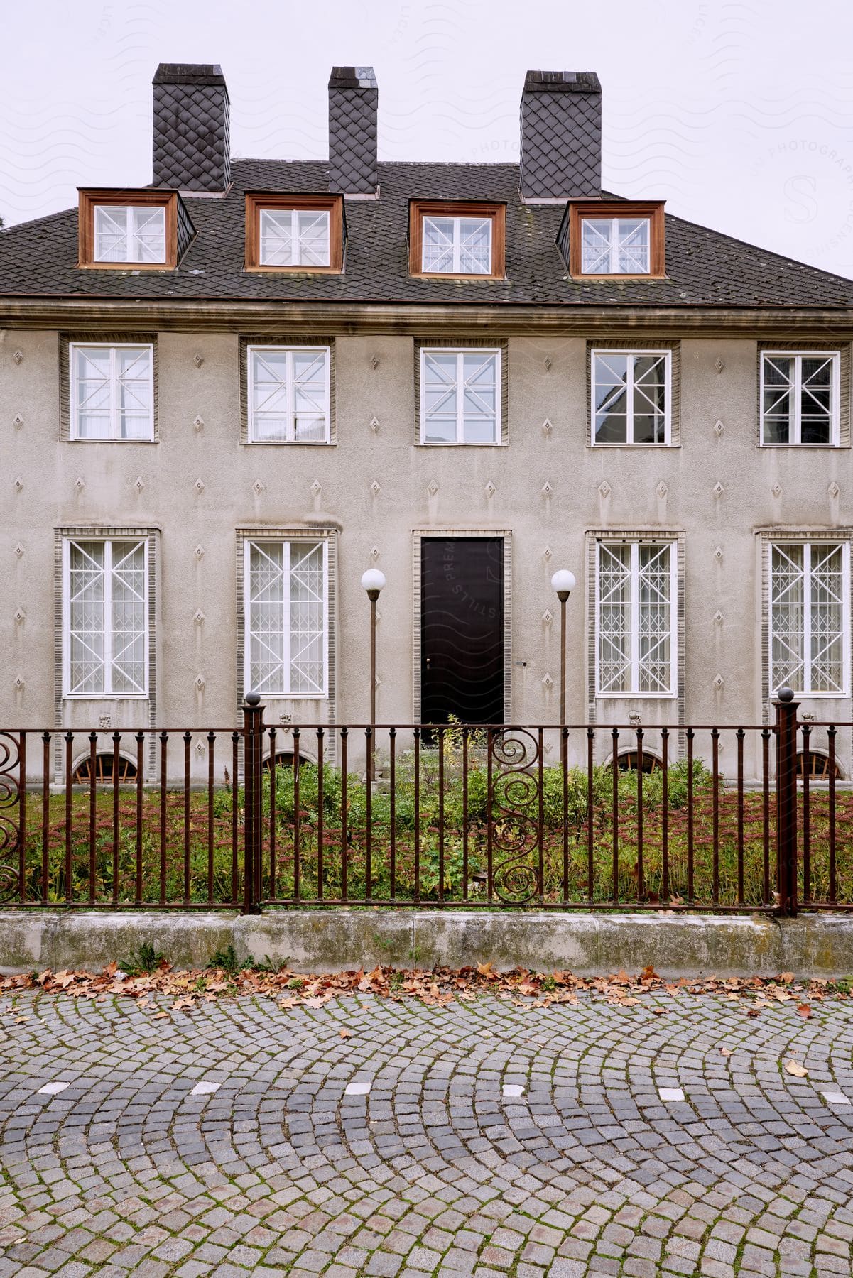 A two-story house with a gray exterior, six windows visible on the front façade and a small fenced yard.