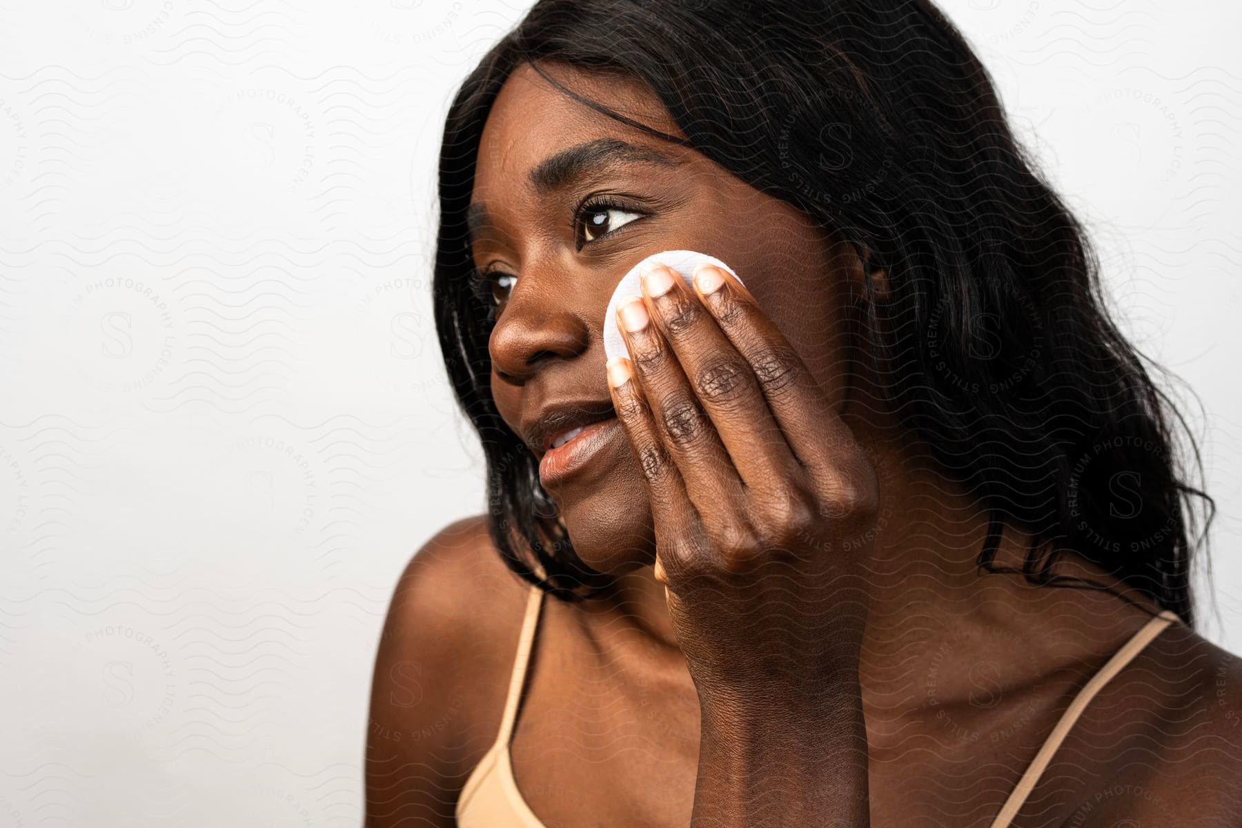 Woman holds a powder puff as she applies makeup to her face