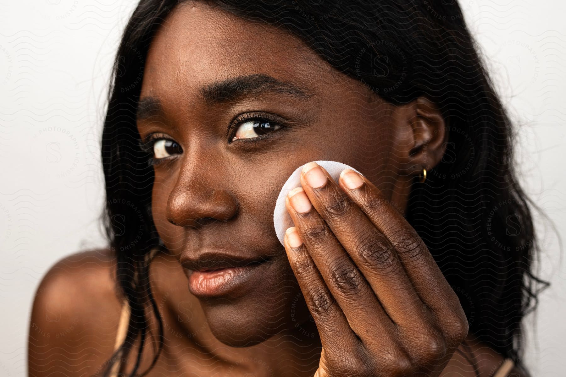Close-up of a woman's face applying makeup removal cotton.
