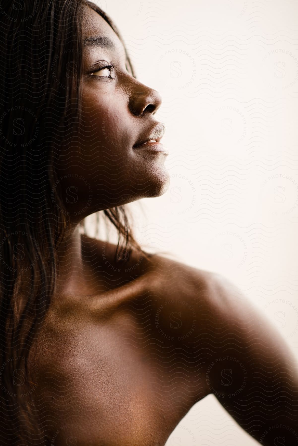 Profile view of a woman gazing upward, with soft lighting and a neutral background.