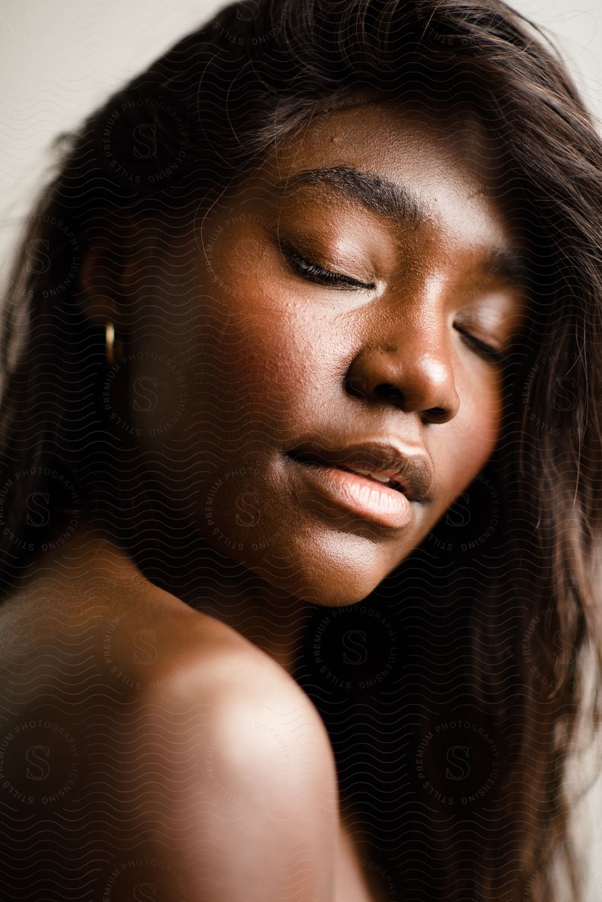 Light shines on a woman's face with eyes closed as her long hair hangs down