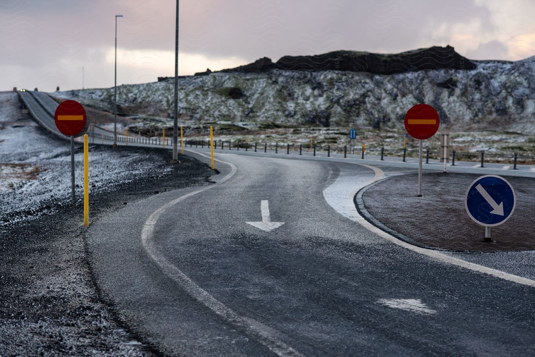 Arrows on an empty rural highway show the way around a traffic circle