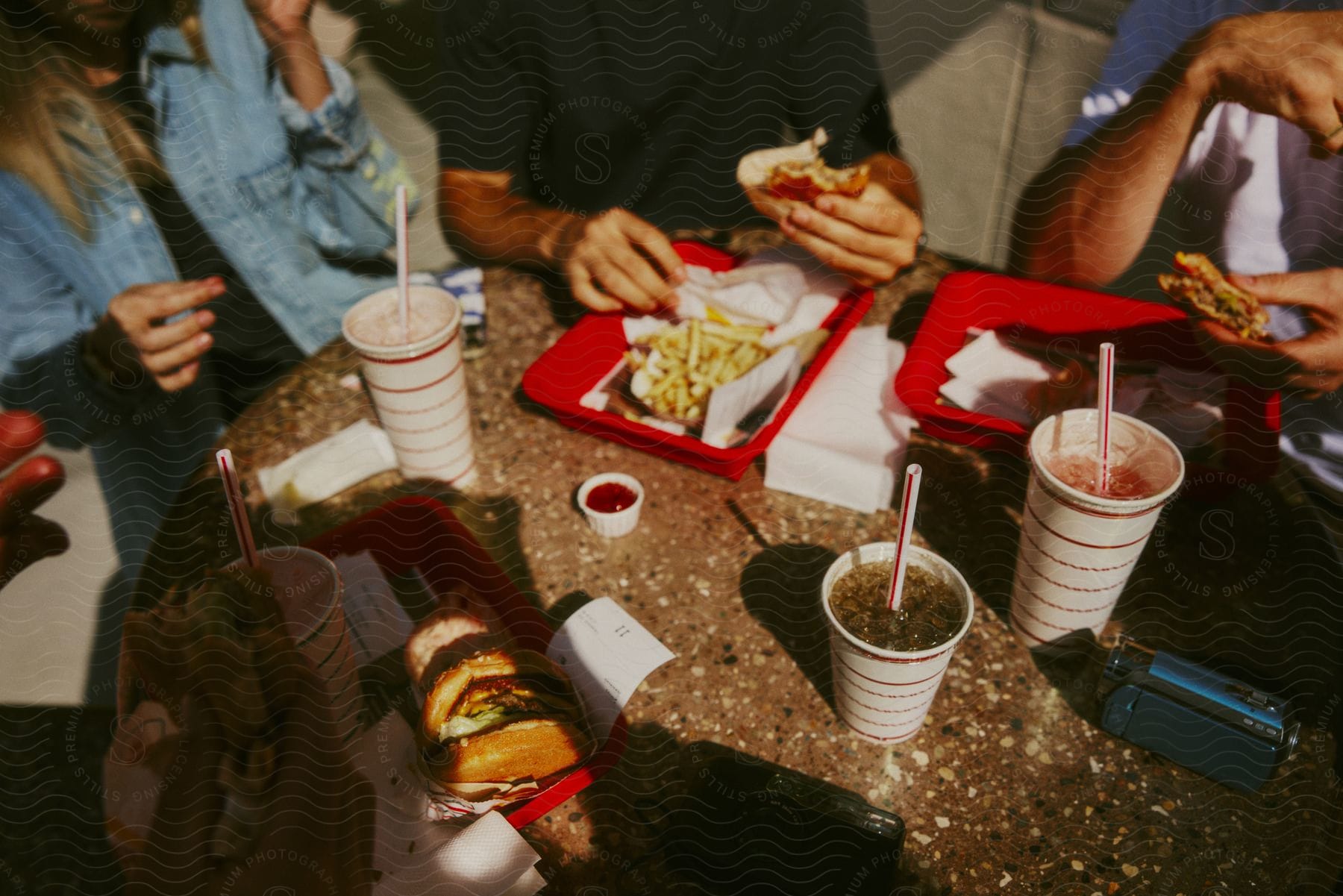 A group of friends sitting at an outdoor table eating burgers and fries