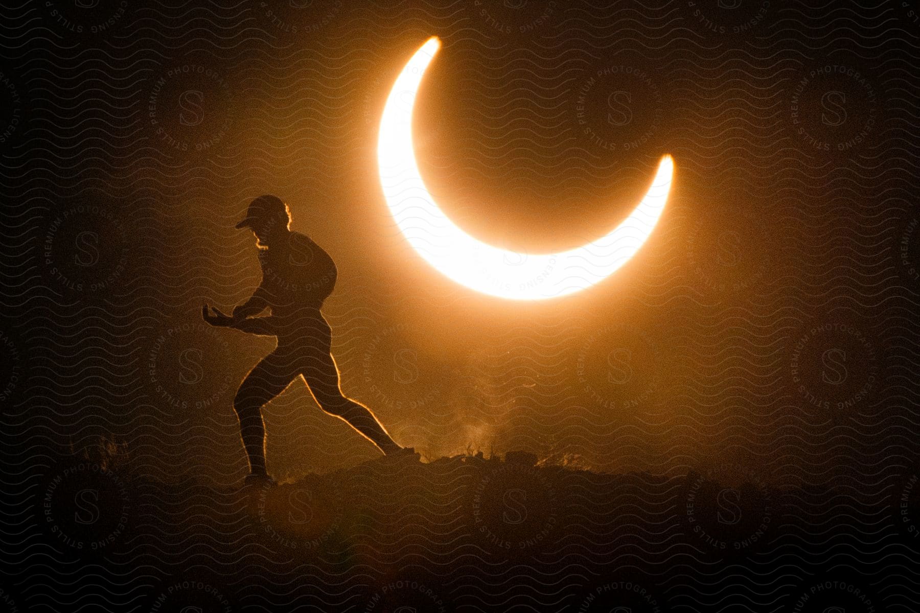 Silhouette of a man hiking a mountain against a night sky with a bright crescent moon.