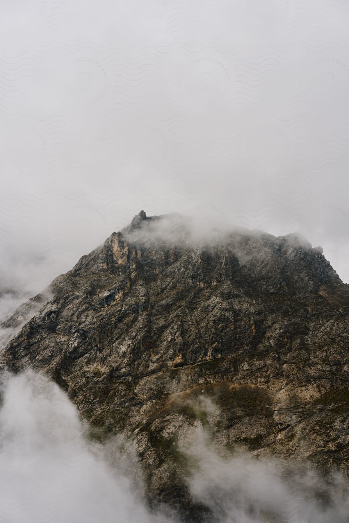 Clouds surround a rough mountain peak.