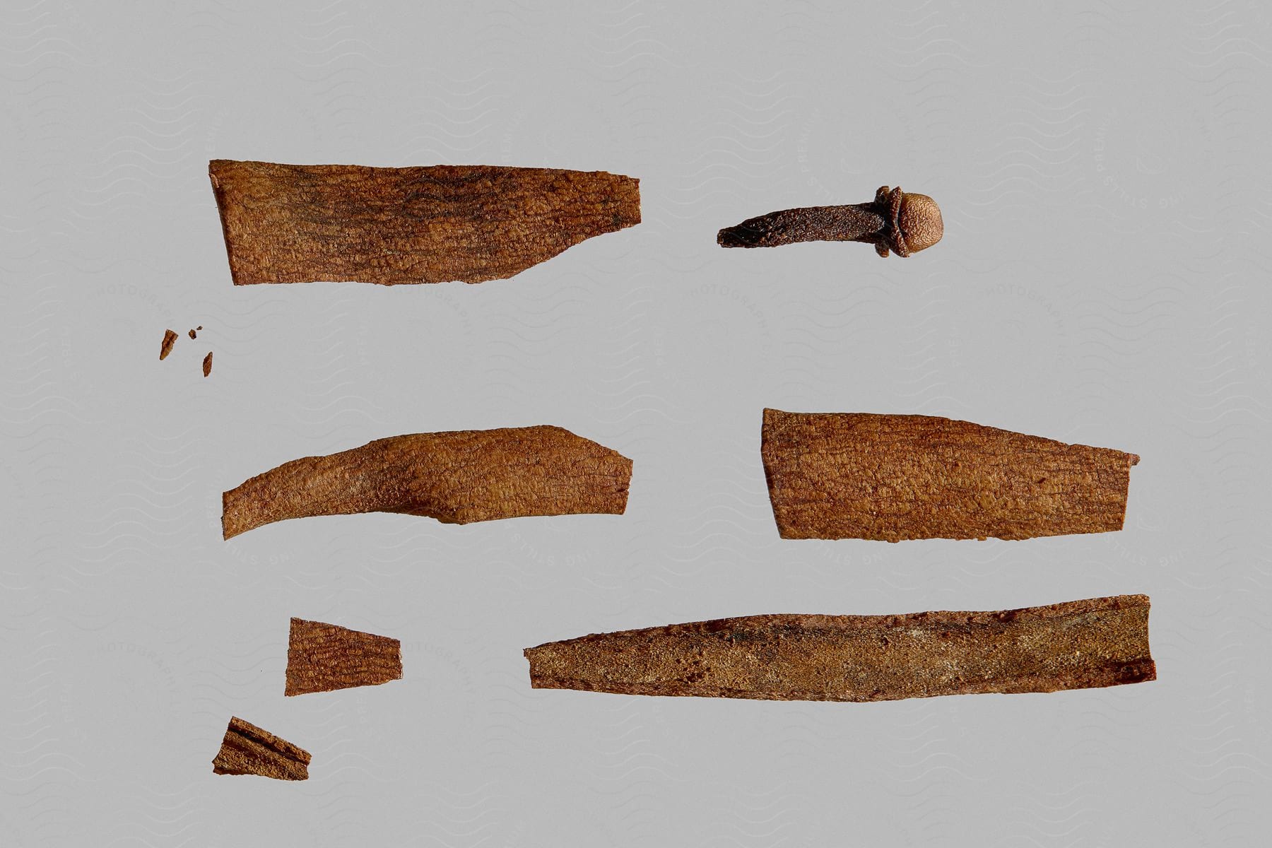 Broken pieces of wood and a rusty nail are laid out on a white surface