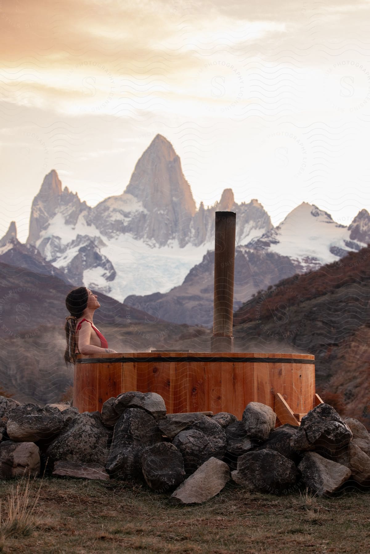 Woman relaxing in an outdoor hot tub with mountains in the distance