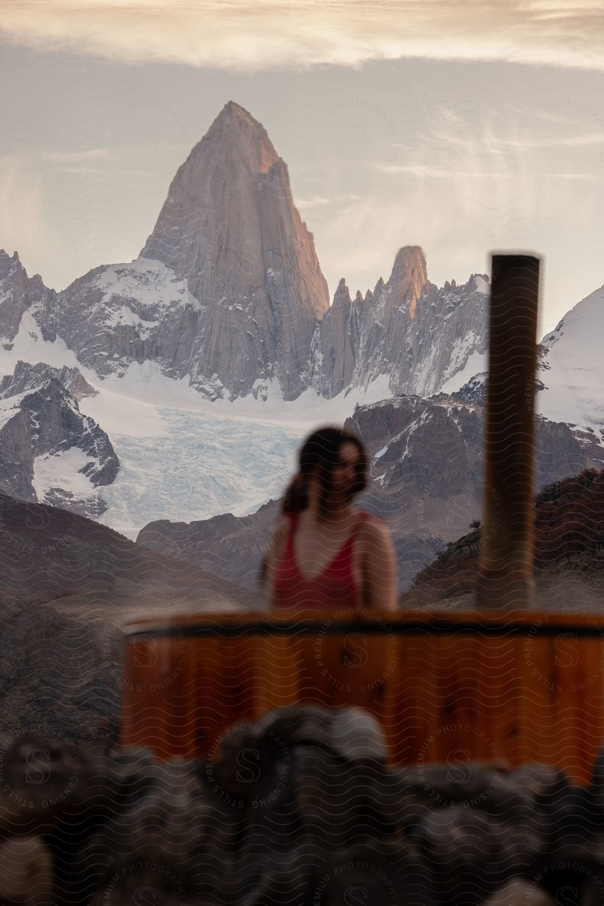 Woman standing outside near a hot tub with mountains in the distance