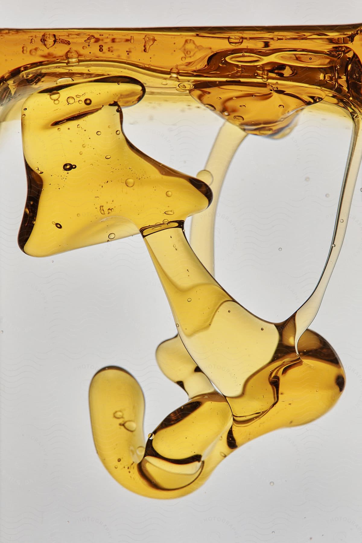 Stock photo of amber syrup floats on the surface and forms mass in the liquid.
