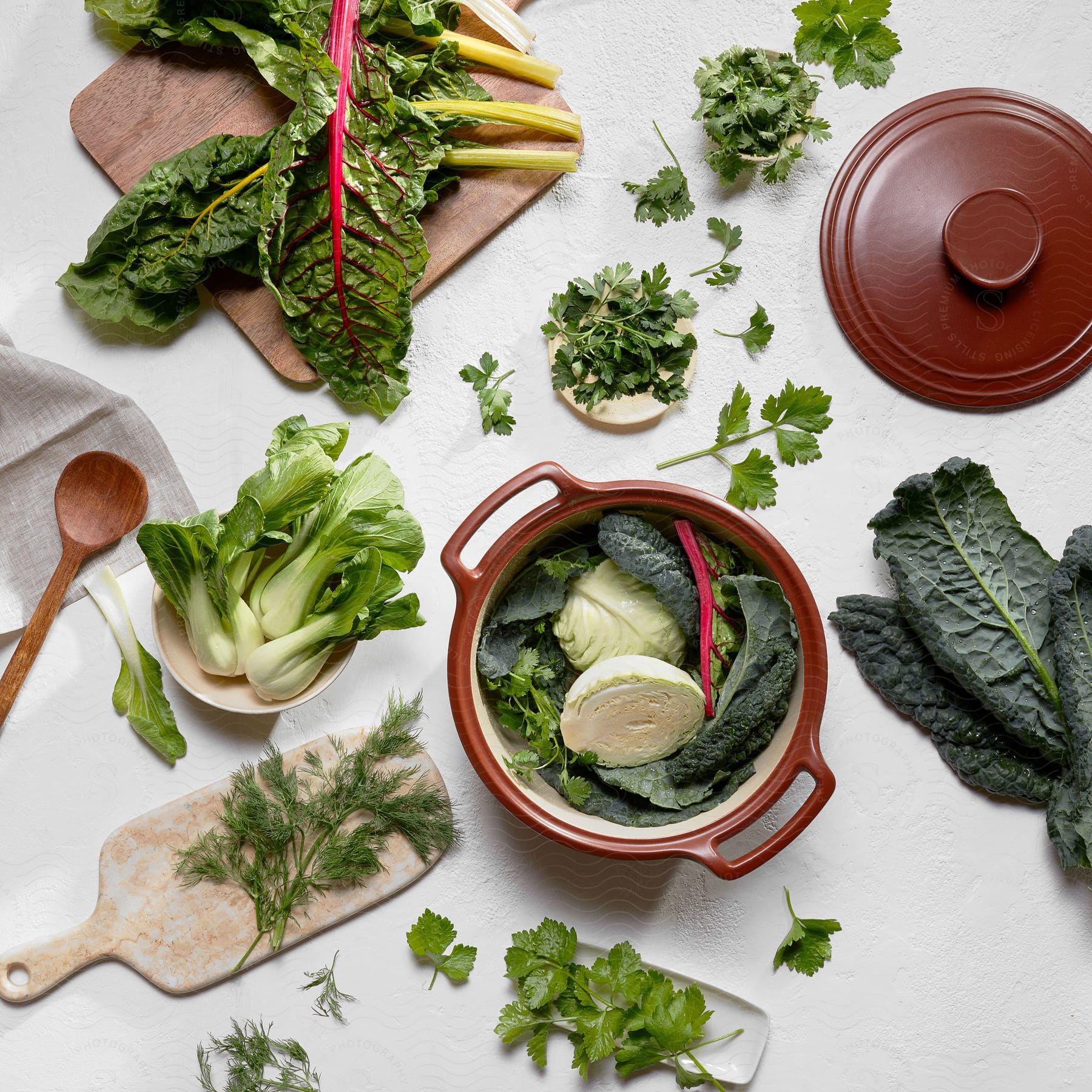 Fresh vegetables separated on kitchen boards and bowls on a white table.