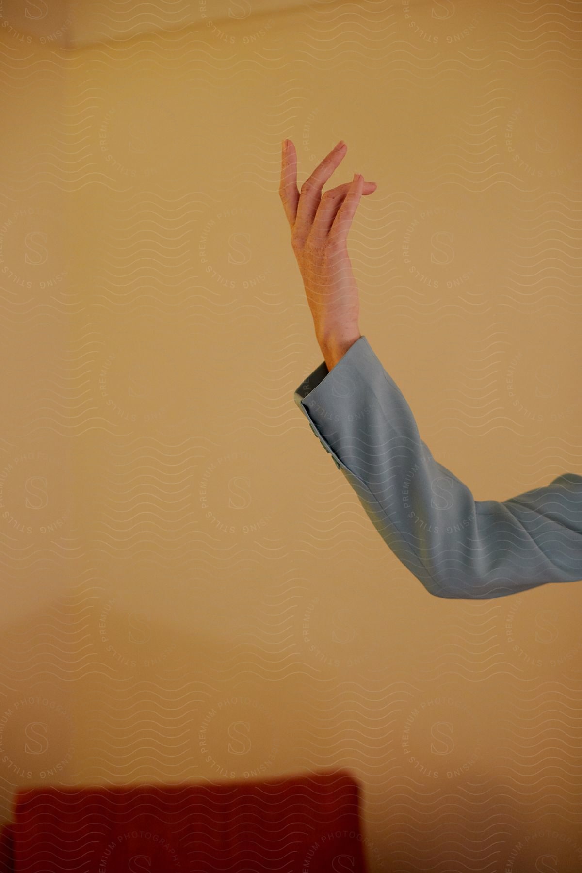 The hand is raised against a yellow background, with the fingers positioned as if they are snapping.