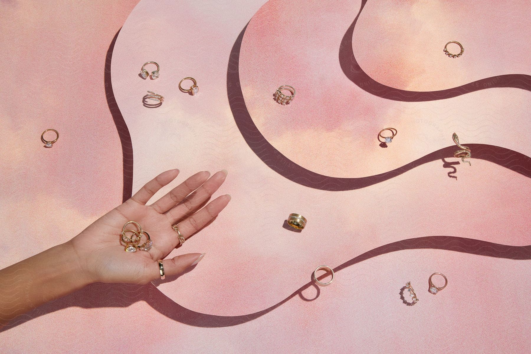 Female model holds rings over surface strewn with different styles of rings.