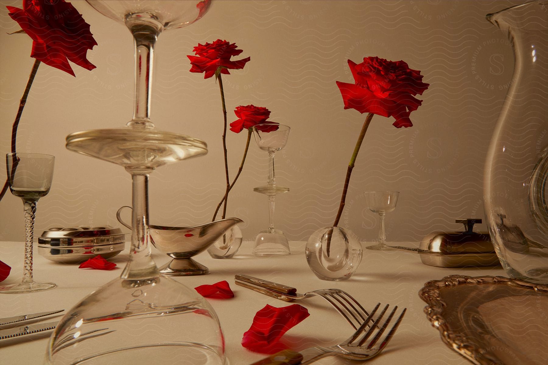 Dining table decorated with glass goblets and red roses. The room is softly lit, creating a romantic atmosphere.