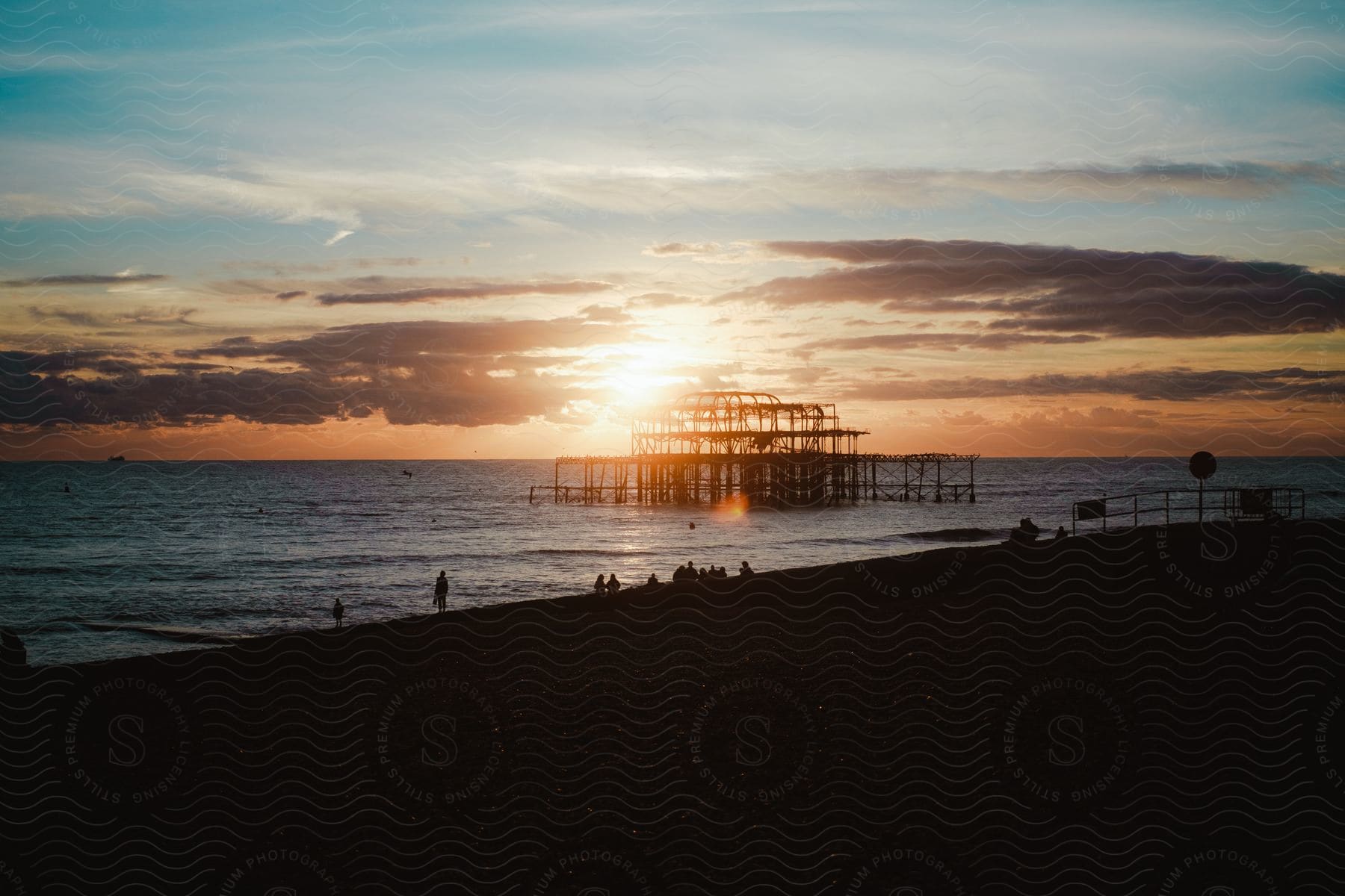 A wooden structure stands in shallow ocean water near the shoreline at dusk.