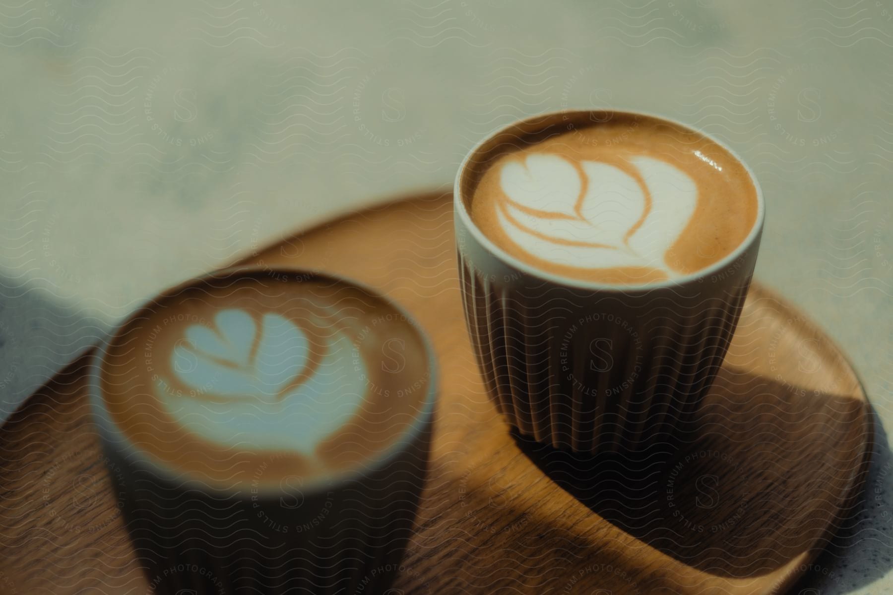 Two cups with cappuccino decorated with a flower and heart.
