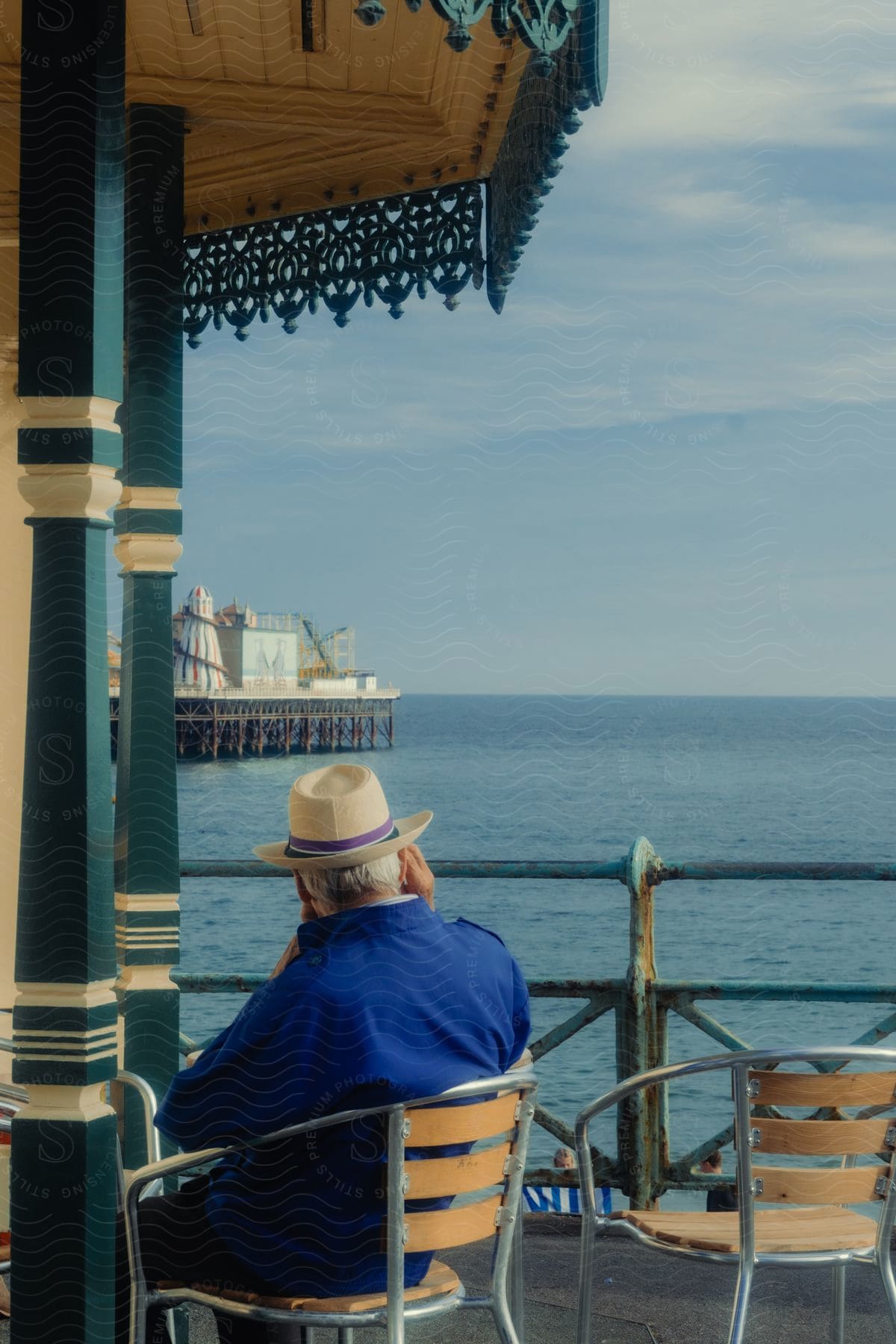 View of an elderly man sitting in a chair on a seaside dock