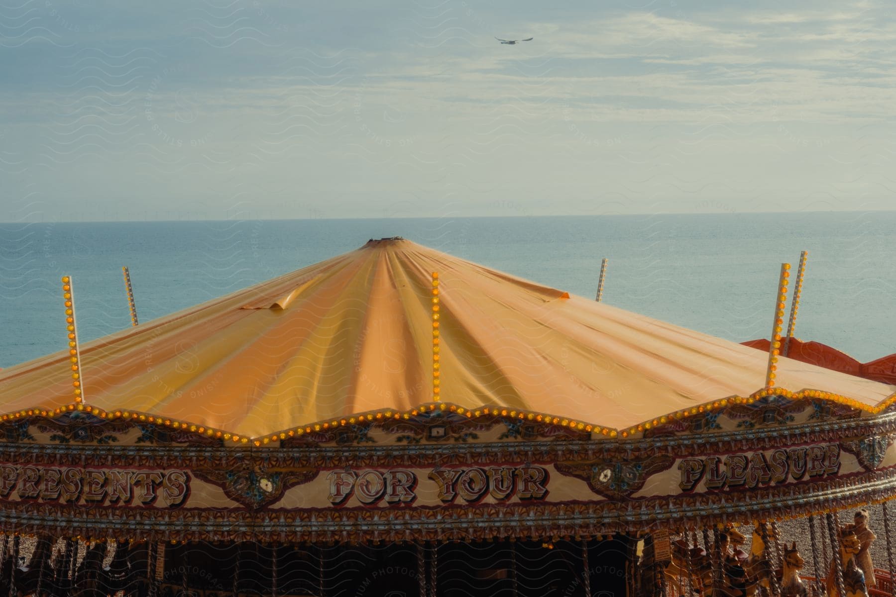 Tent topping a carousel as people are riding and having fun along the coast