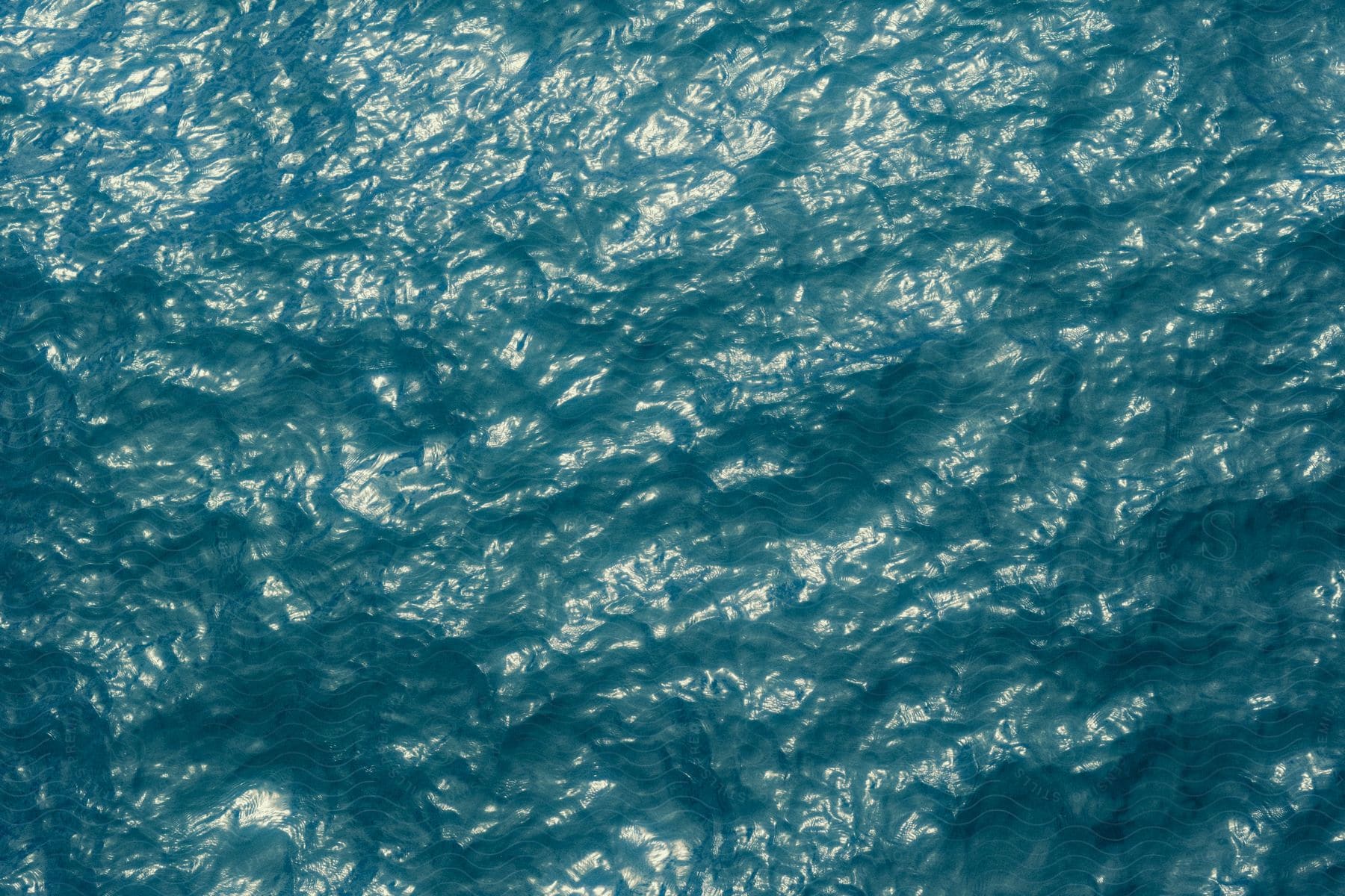 A water surface that is reflecting natural light with small ripples