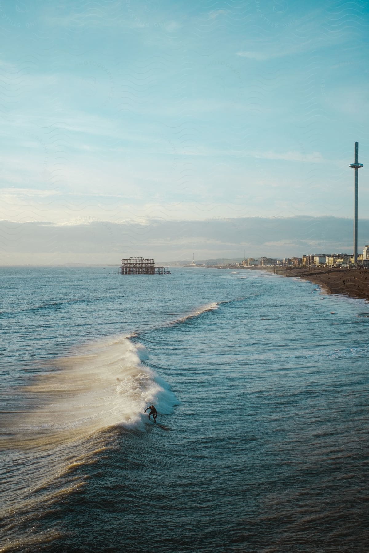 Houses along the coast as a surfer rides a wave into shore