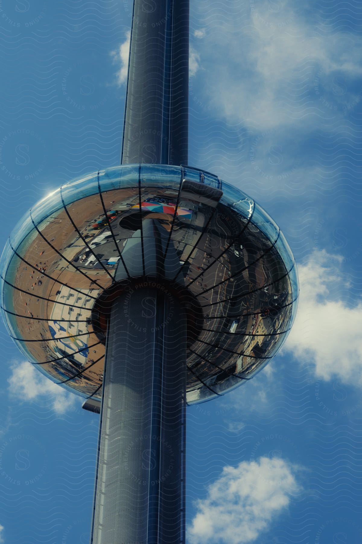 Observation tower with reflective surface against a blue sky with clouds.