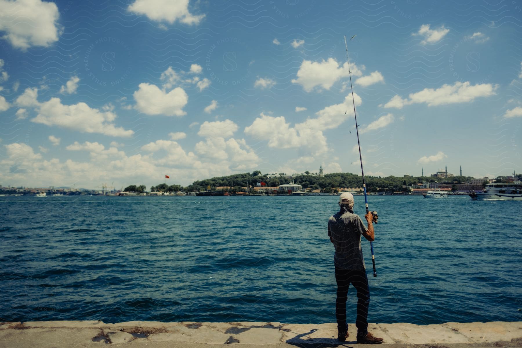 A man fishing in the lake with a land in the distnace