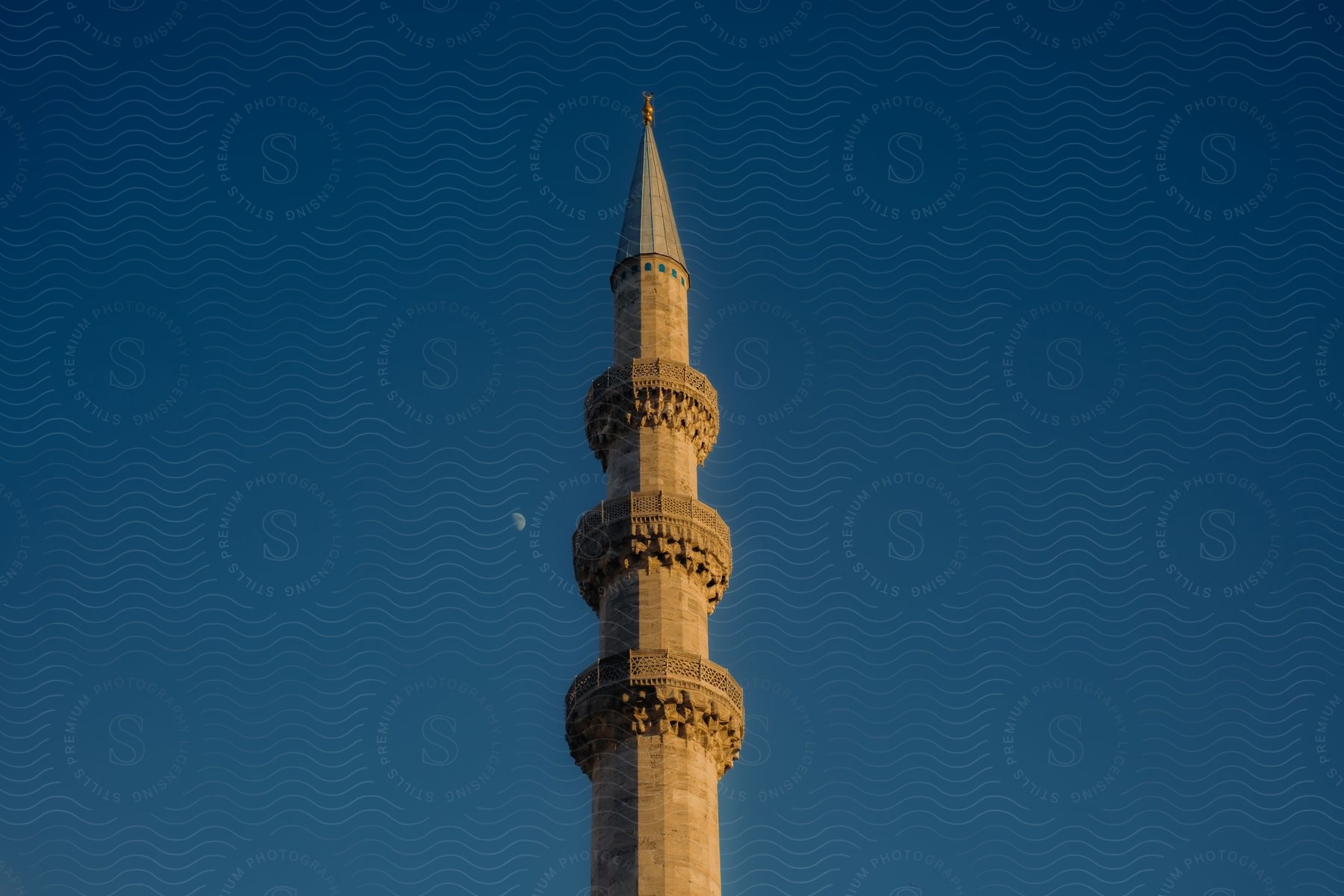 Tower stands tall in a deep blue sky with the moon in the distance