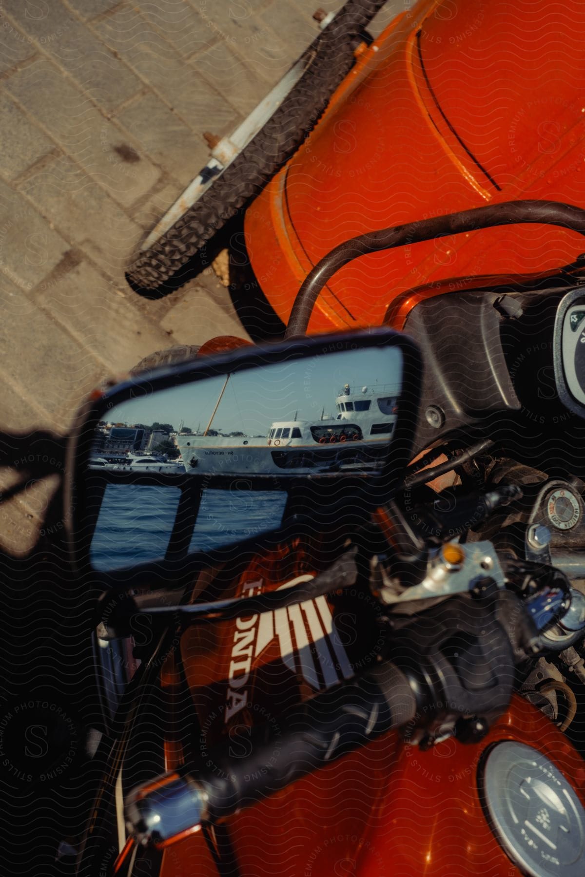 Close-up of a motorcycle's rear view mirror reflecting yacht in the sea.