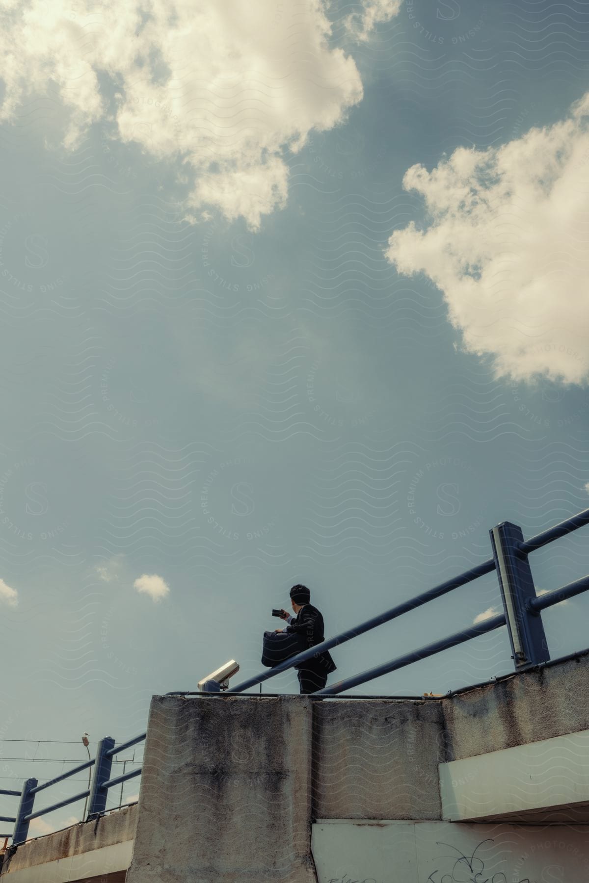 Man on a bridge in formal clothes and a briefcase taking a selfie.