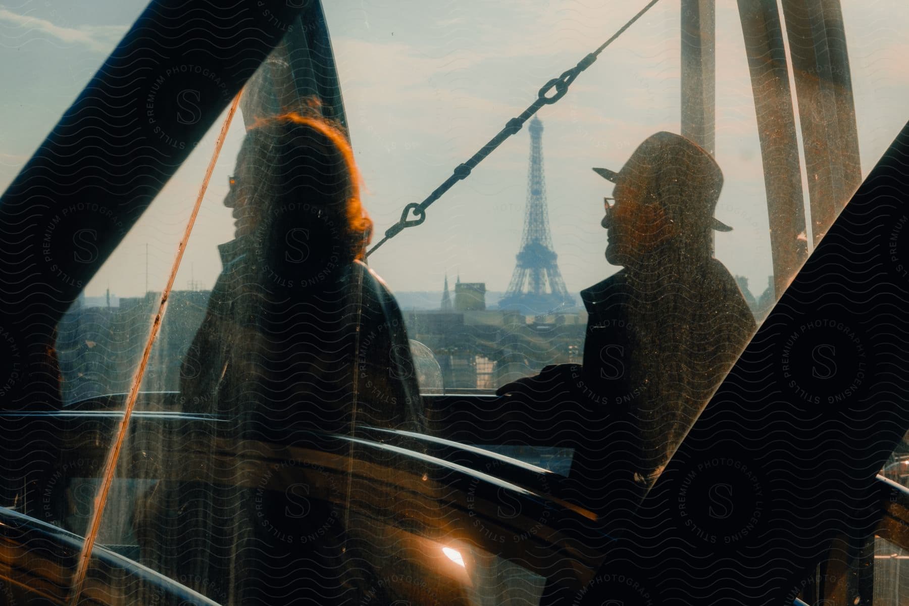 Man and woman tourists walking in a mirrored building with a view of the Eiffel Tower on the horizon