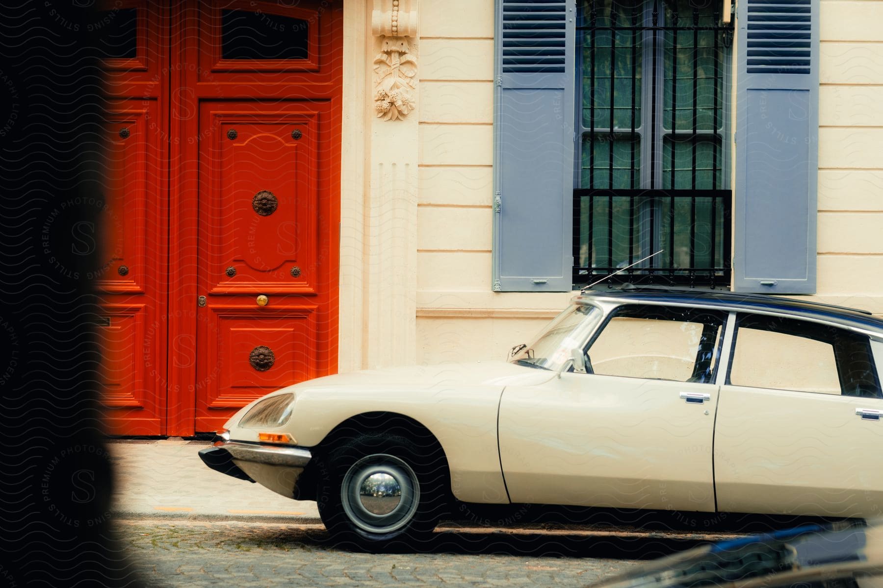 A sedan is parked outside of a building with a bright red door.