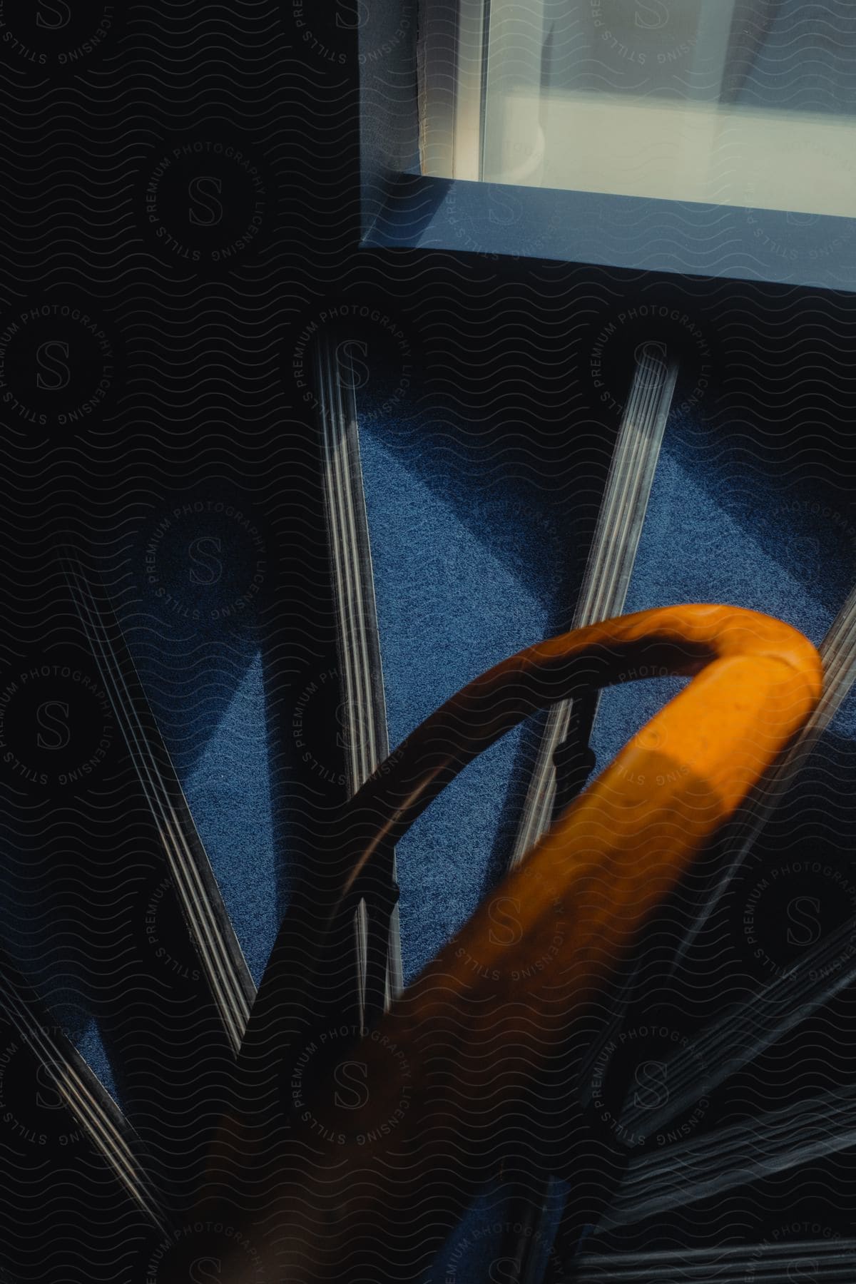 A wooden railing on a staircase with blue carpeting