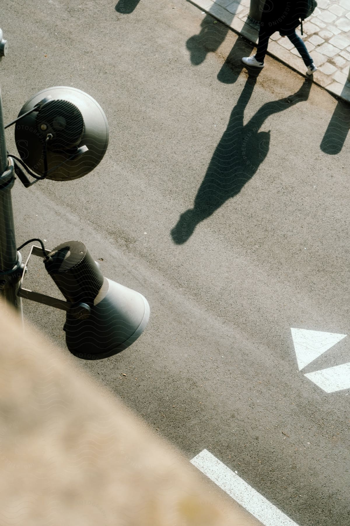 Legs of a person walking on the asphalt street in an urban environment and next to a pole with two light reflectors.