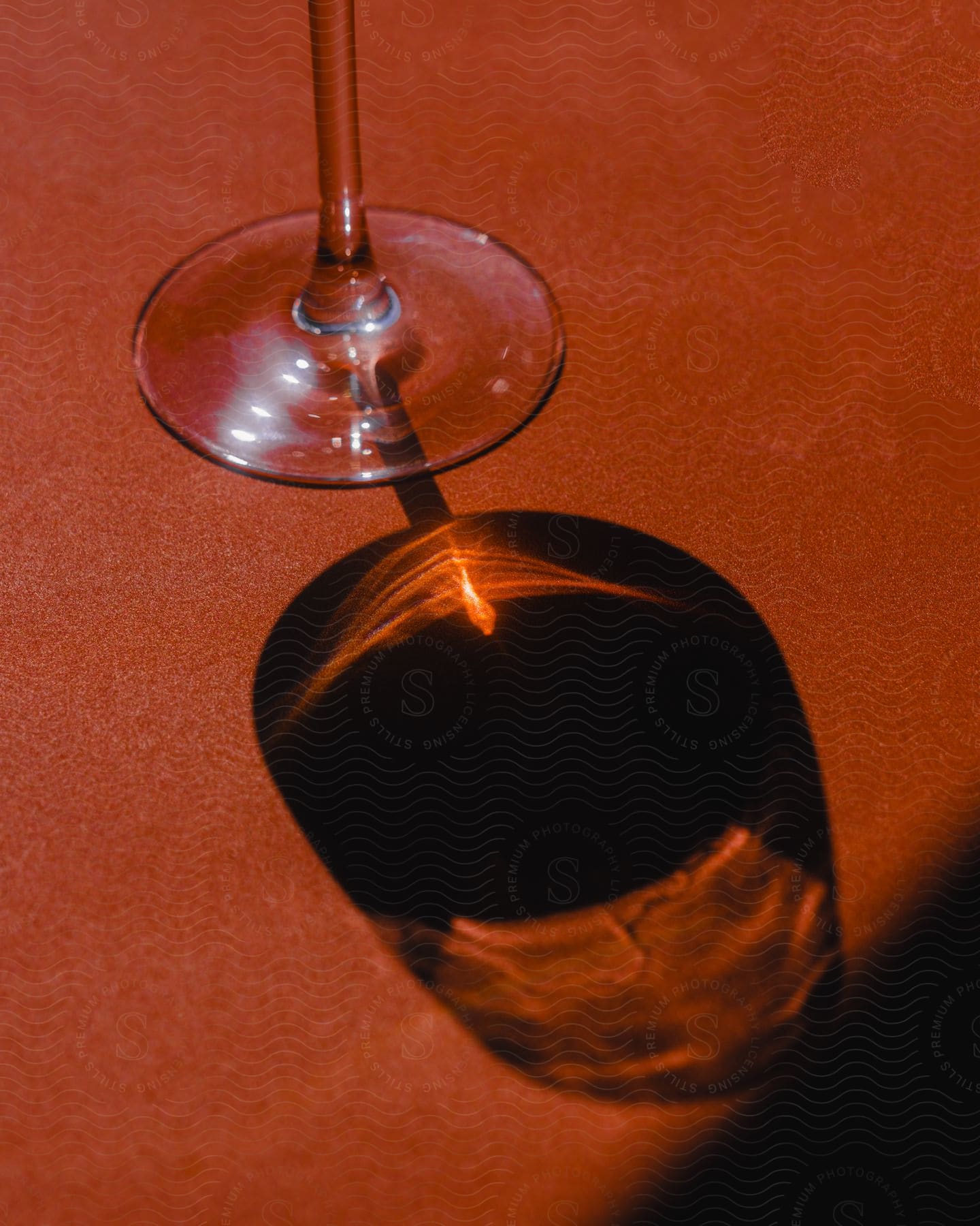 A dark shadow of a glass goblet on an orange surface